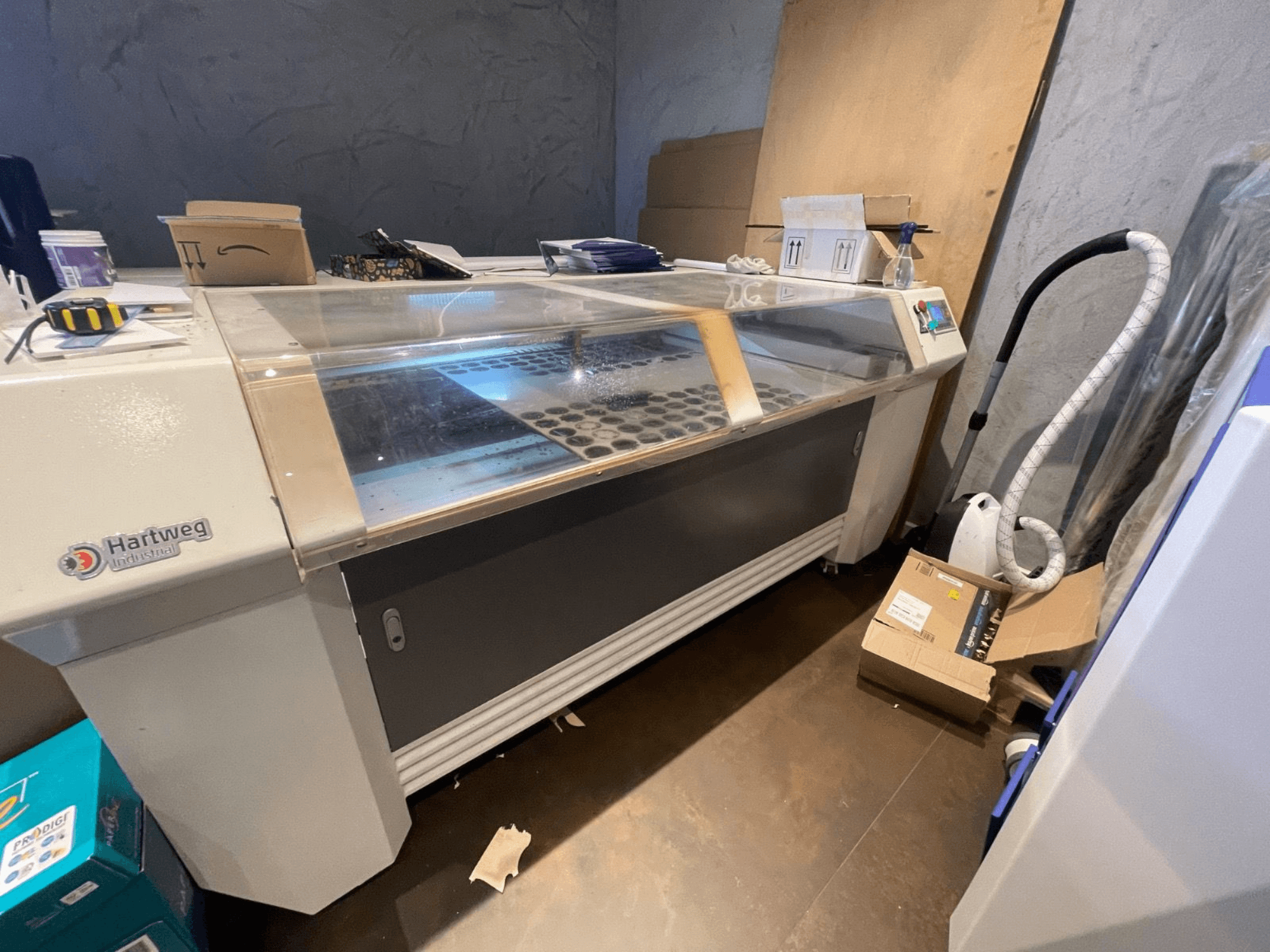 CO2 laserový řezací stroj Bodor CL-1610XUF v bočním pohledu, znázorňující pracovní plochu s otvory pro materiál a ovládacím panelem.