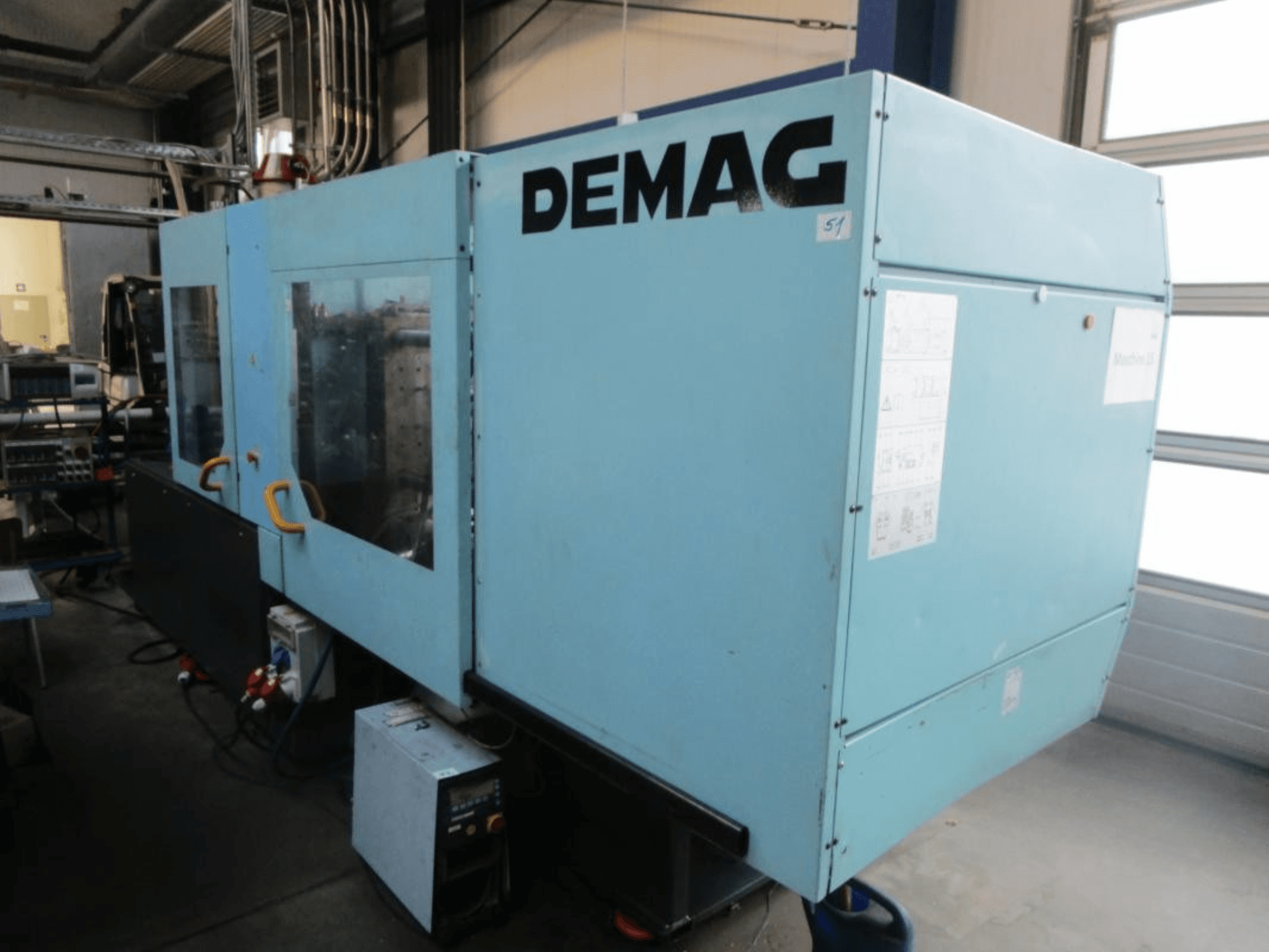 Pohled zepředu na hydraulický vstřikovací stroj DEMAG Ergotech 150-610 Viva s viditelným ovládacím panelem a rukojeťmi.