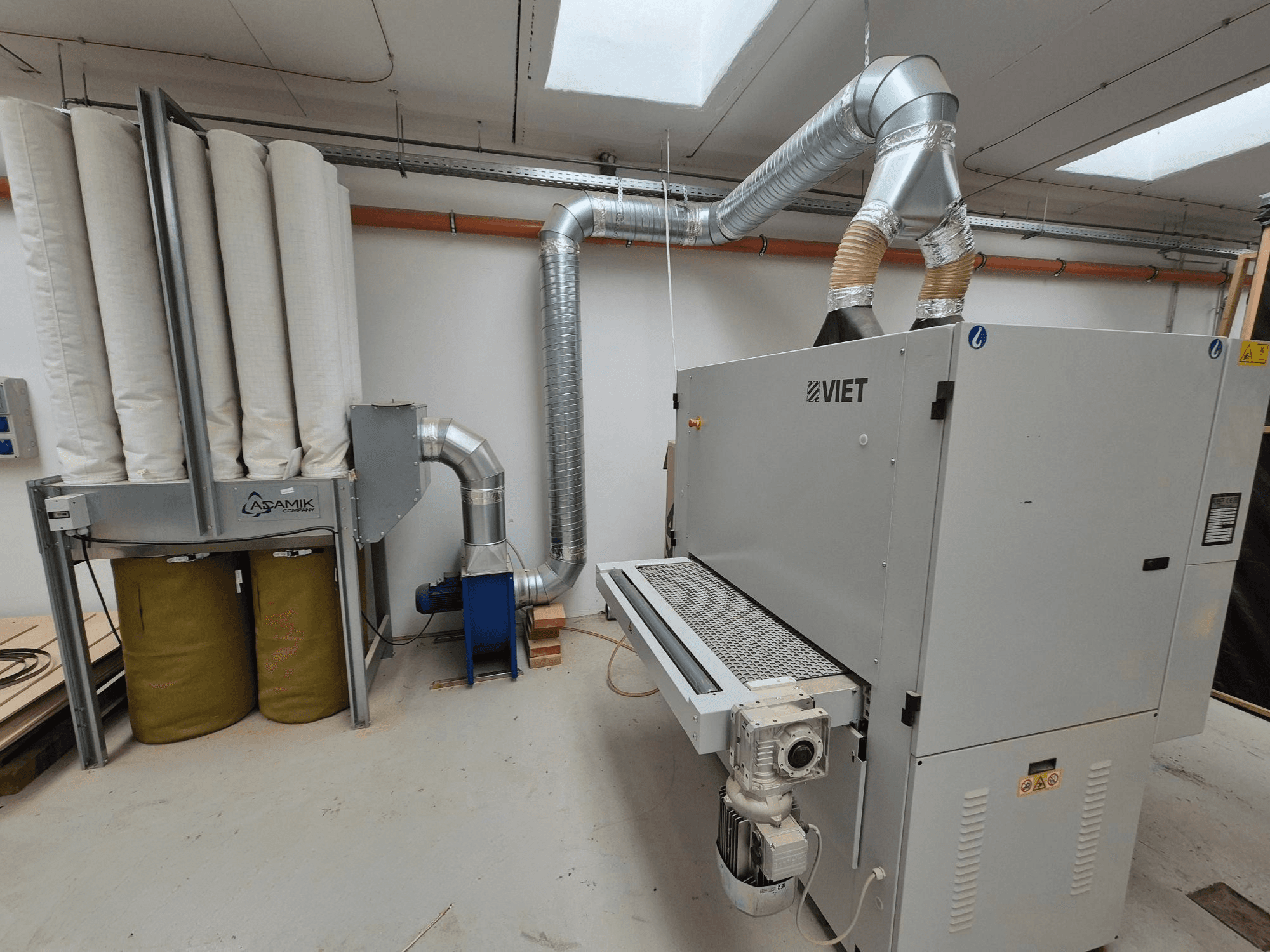 Systém odsávání prachu Viet s válcovými filtry a stříbrným výfukem, pohled zepředu v dílně.