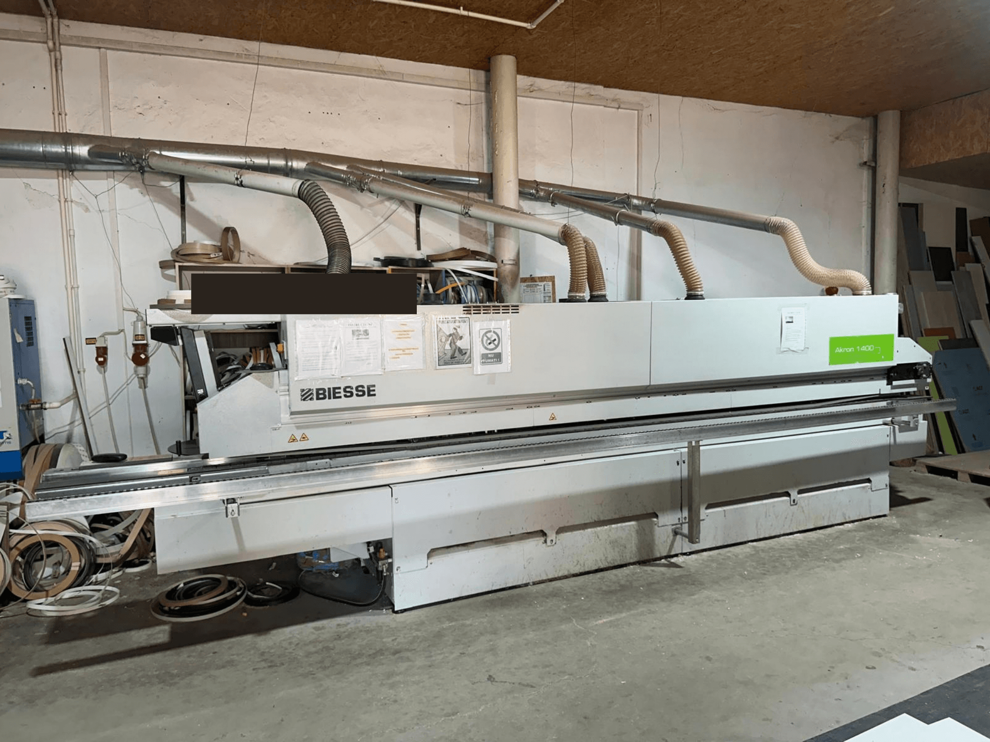 Olepačka hran BIESSE AKRON 1440 A, pohled zepředu, s viditelným ovládacím panelem a prvky odsávání prachu v dílenském prostředí.