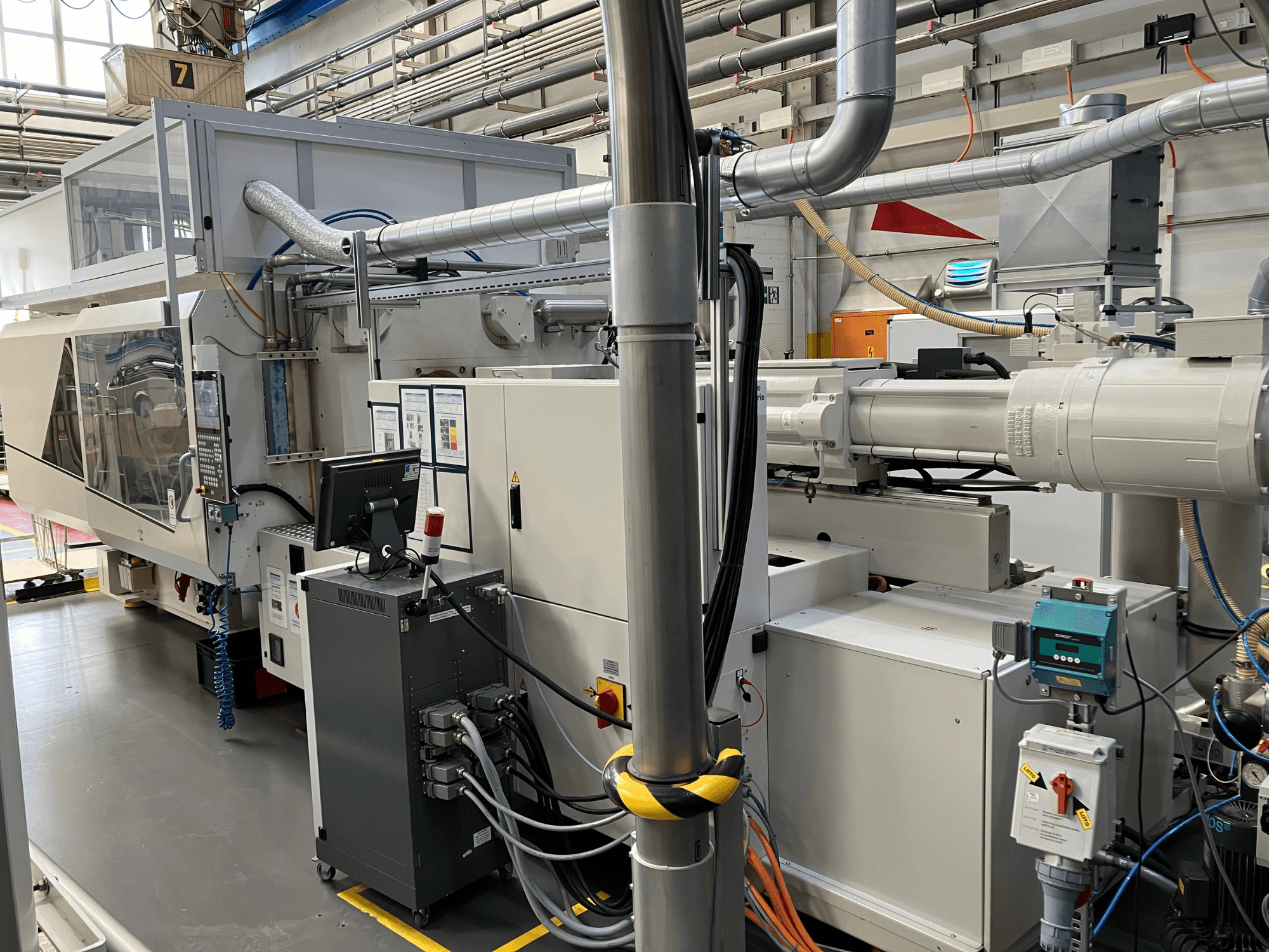 Průmyslové stroje s ovládacím panelem, pohled zepředu, s potrubím, elektrickými součástmi a bezpečnostními prvky.