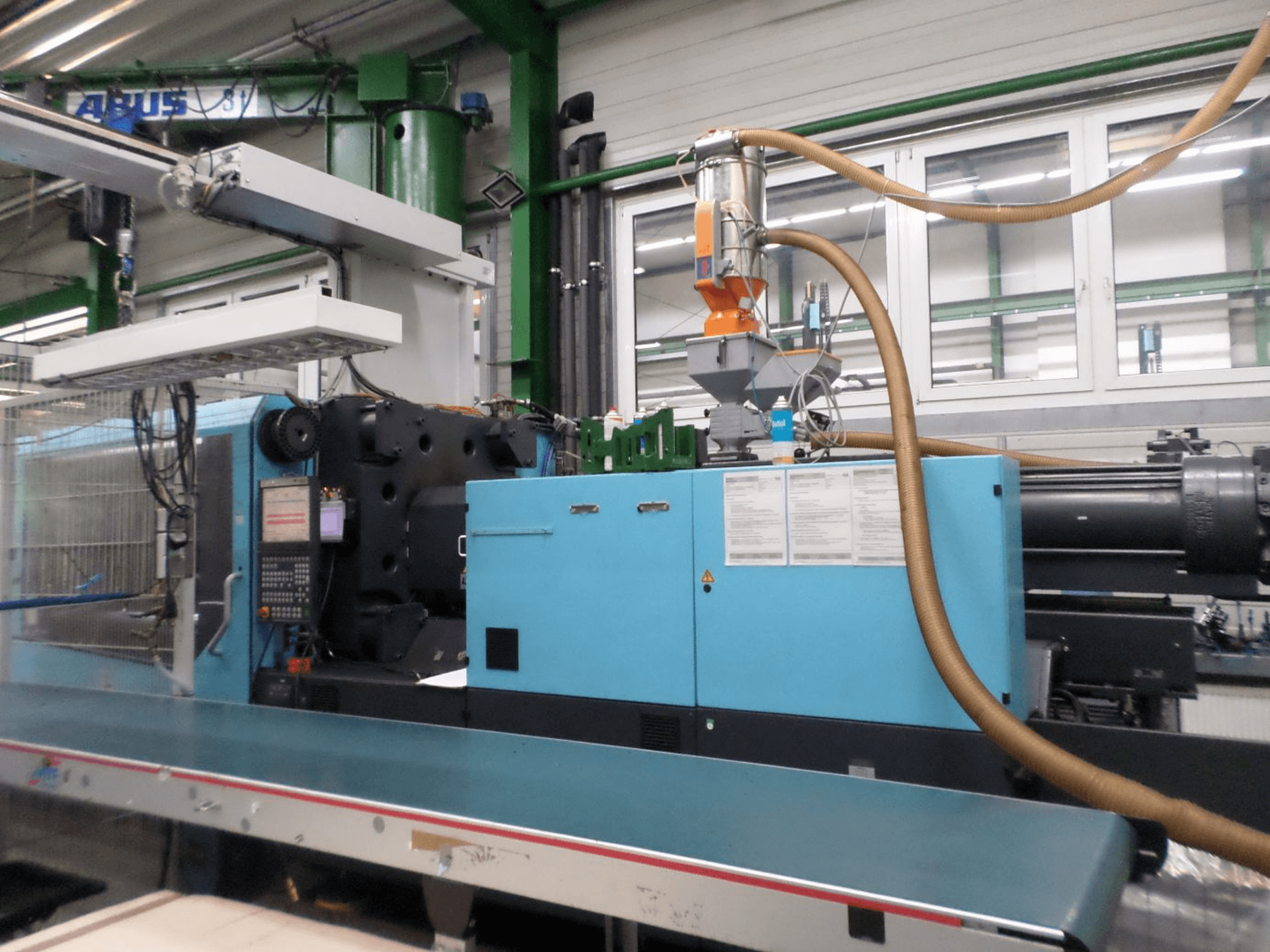Pohled zepředu na hydraulický vstřikovací lis DEMAG D 420, na kterém je vidět ovládací panel, násypka a hydraulické komponenty.