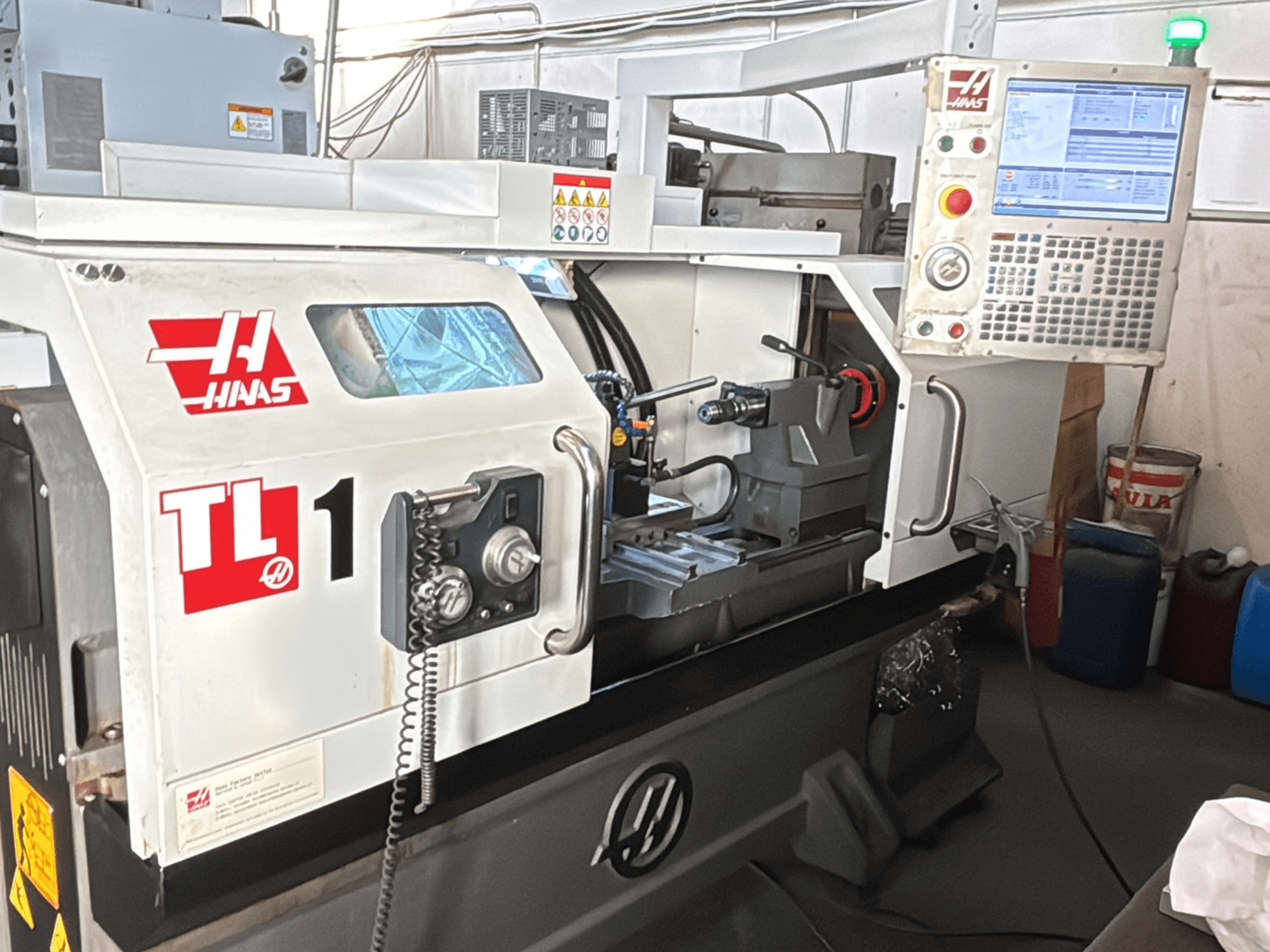 CNC soustruh Haas TL-1, pohled zepředu, ovládací panel s displejem, držák nástrojů a bezpečnostní štítky.