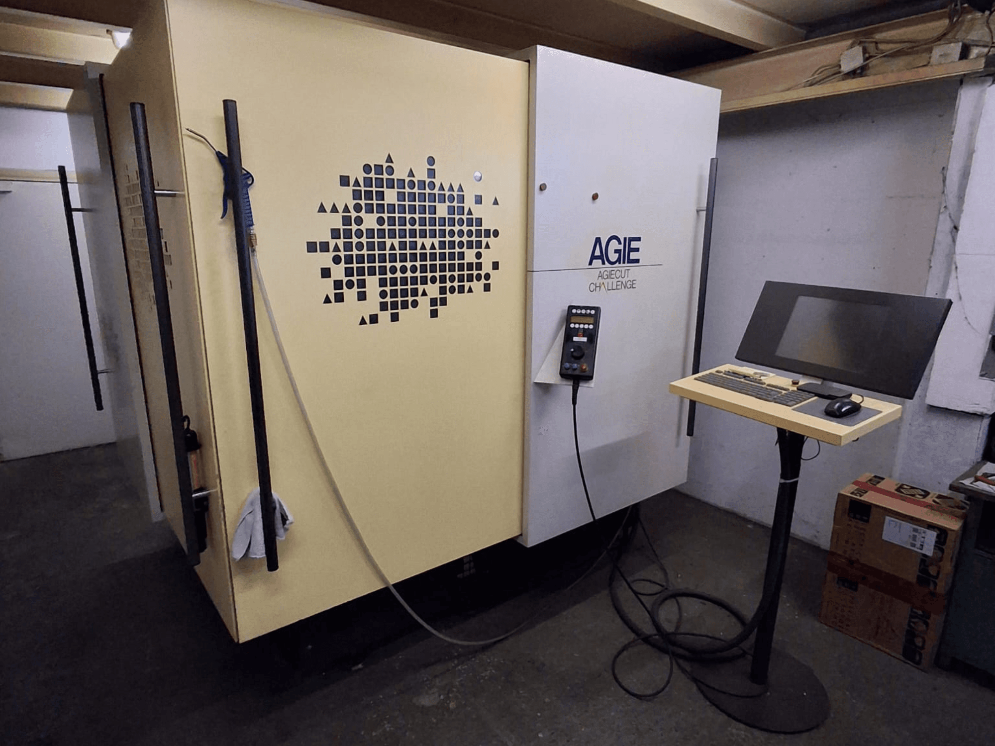 Dvouvodičový elektroerozivní stroj AGIE Agiecut Challenge v dílně, s ovládacím panelem a monitorem na stojanu, pohled zepředu.