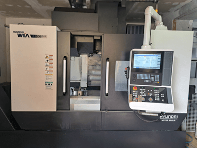 Stroj Hyundai WIA F500 Plus CNC v čelním pohledu, s digitálním ovládacím panelem a bezpečnostními štítky.