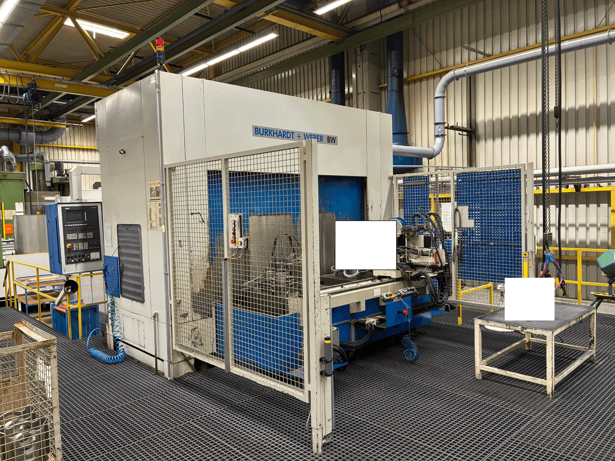 Obráběcí centrum Burkhardt + Weber BW, pohled zepředu, s ovládacím panelem a bezpečnostním krytem, umístěné v průmyslovém prostředí.