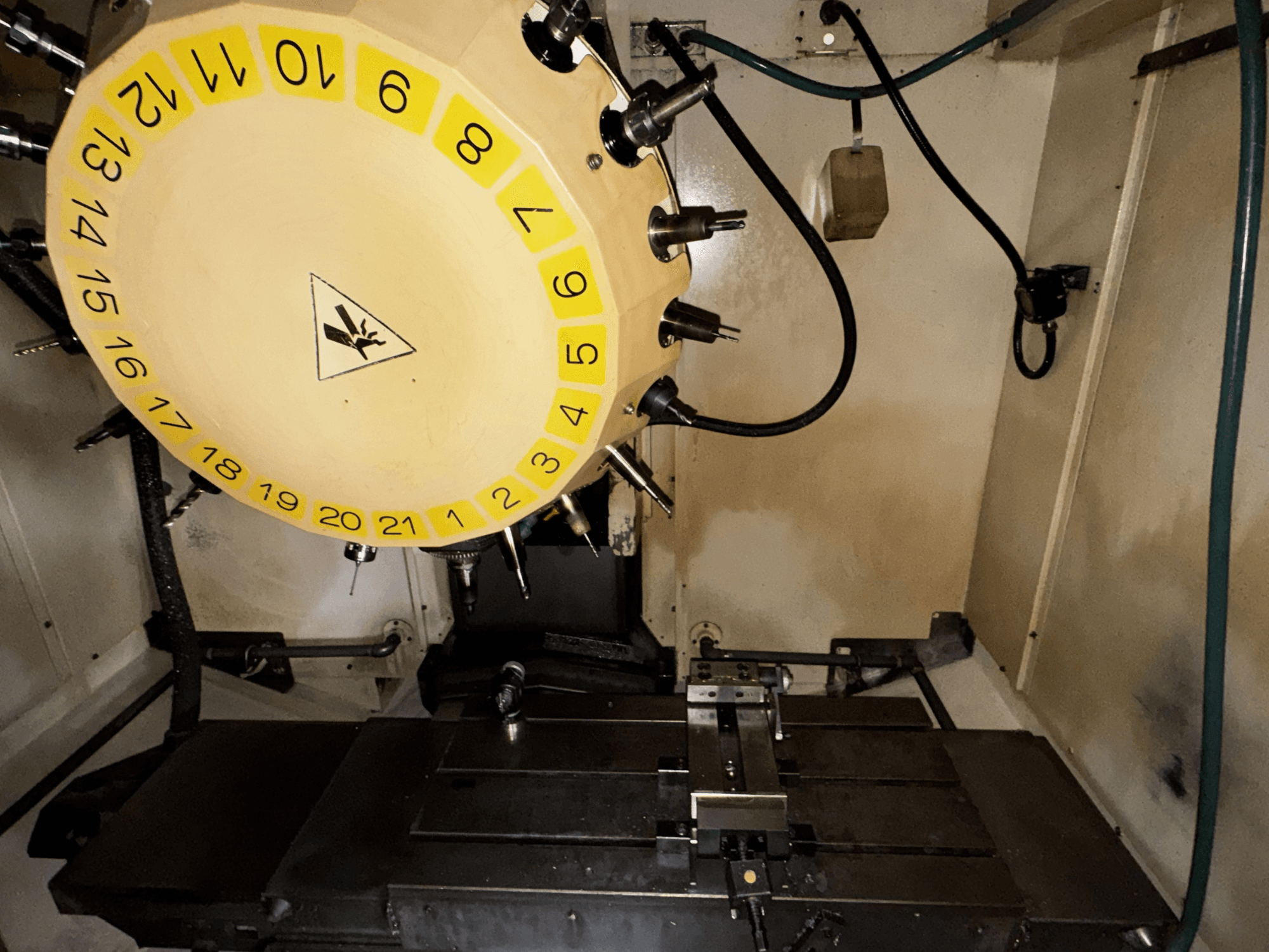 Pohled do interiéru vertikálního obráběcího centra FANUC Robodrill alpha-T21iFL s viditelným karuselem nástrojů a obráběcím stolem.