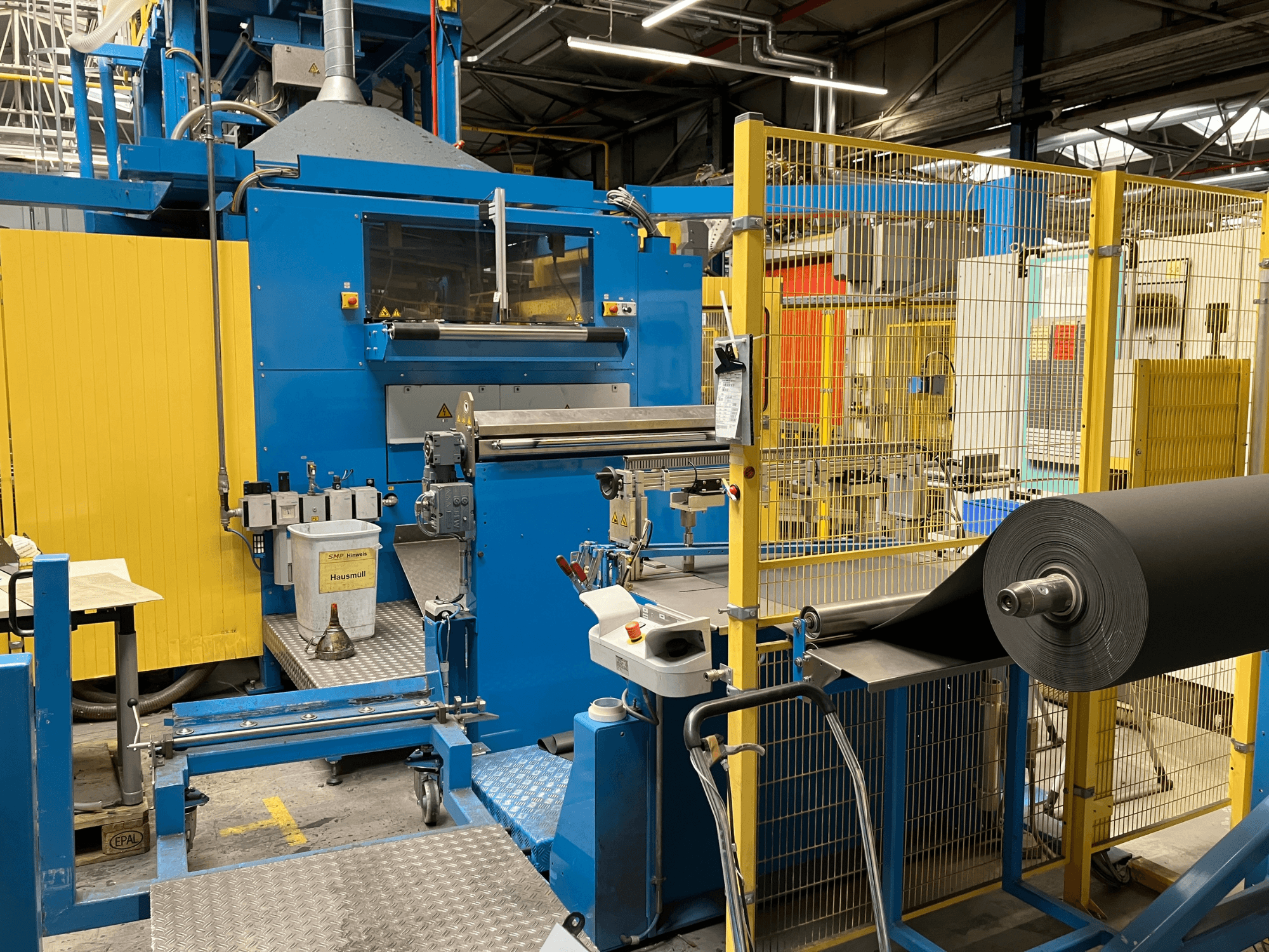 Stroj na zpracování plastů KIEFEL KLS 86/235 při pohledu zepředu, s rolí černého materiálu a ovládacím panelem.