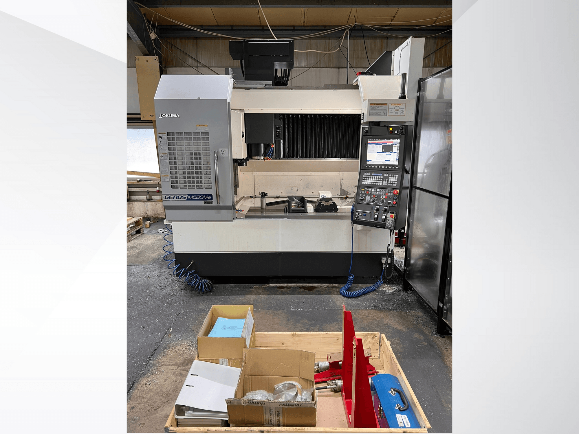 Vertikální obráběcí centrum Okuma GENOS M460V-5, pohled zepředu, s viditelným ovládacím panelem a nástroji na pracovním stole.