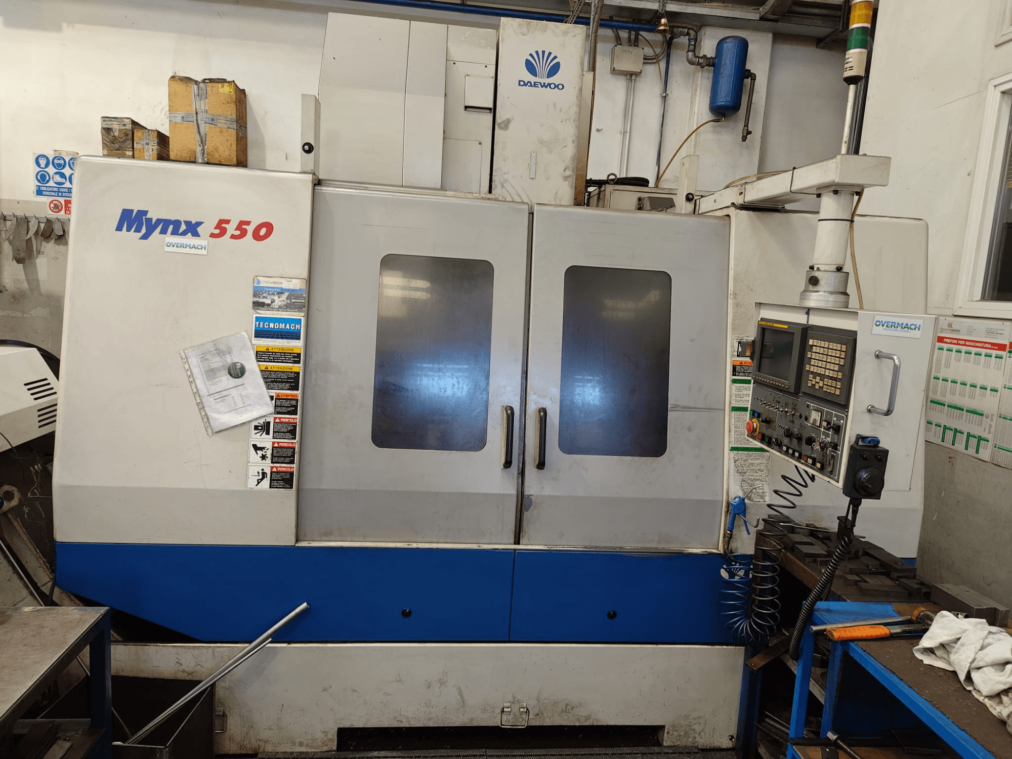 Vertikální obráběcí centrum DAEWOO MYNX 550, pohled zepředu, s ovládacím panelem, dvěma velkými dveřmi a bezpečnostními štítky.
