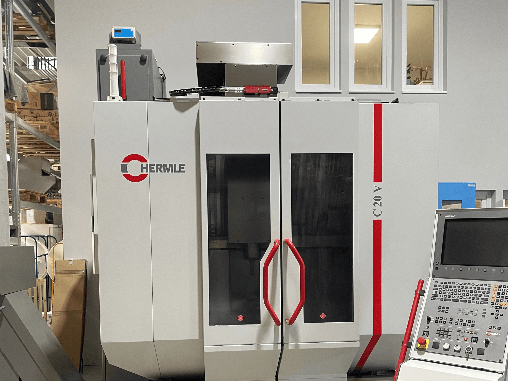 Stroj Chermle C20 V CNC, pohled zepředu, s ovládacím panelem a červenými madly; průmyslový design s velkými prosklenými dveřmi.