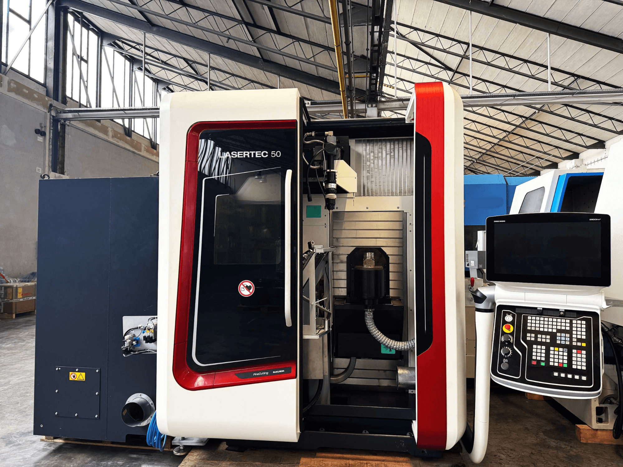 Stroj LaserTec 50 CNC v bočním pohledu, s černobílým ovládacím panelem, viditelným držákem nástrojů a průmyslovým nastavením.