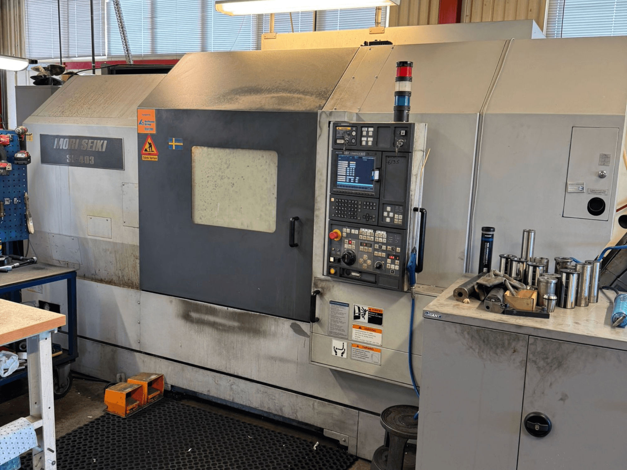 Horizontální soustruh MORI SEIKI SL-403BMC/800 v dílně, ovládací panel a nástroje v okolí, boční pohled.