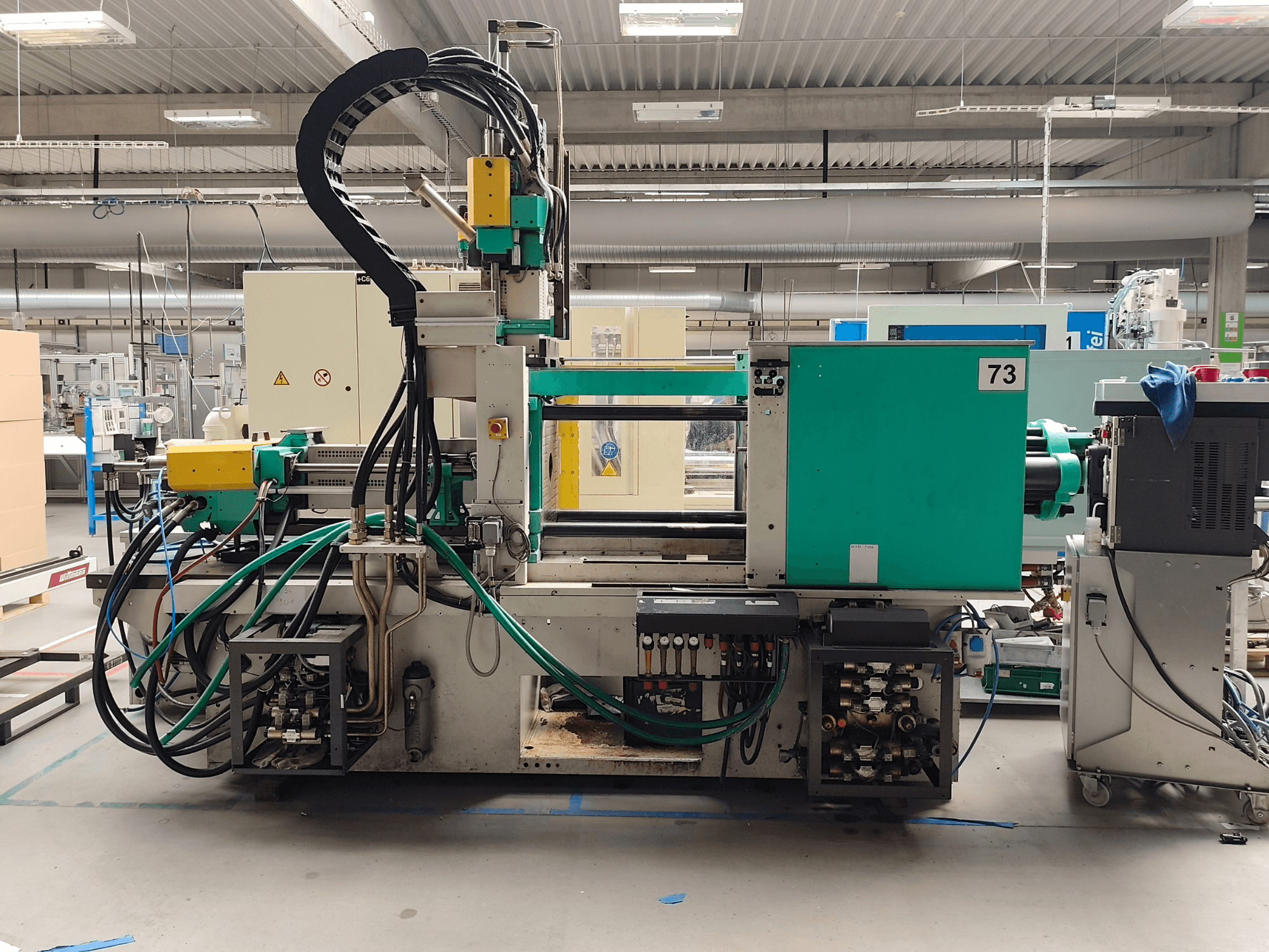 Hydraulický vstřikovací stroj Arburg 420 C 1000-150/60, pohled z boku, s viditelnými hydraulickými přípojkami a ovládacími prvky.