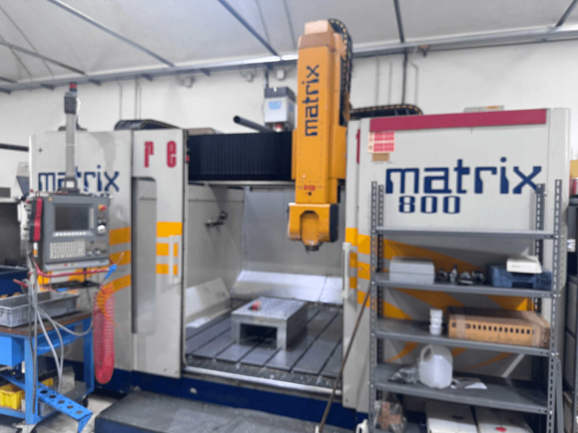 Stroj Matrix 800 CNC v dílenském pohledu, s ovládacím panelem, nástroji a pracovním stolem s různými předměty.