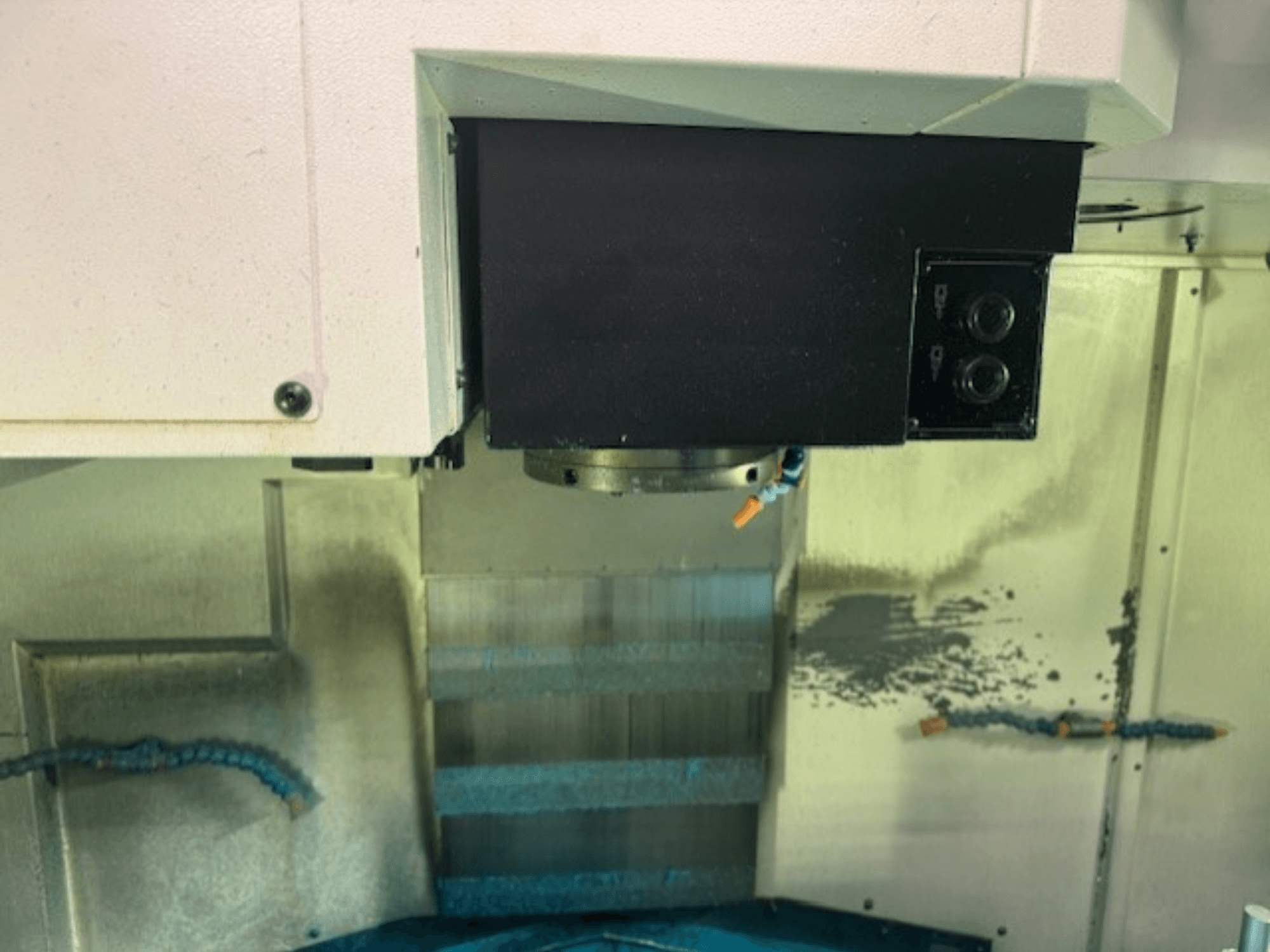 Detailní záběr ovládacího panelu CNC frézky a držáku nástrojů s detaily značky, tlačítky a pracovní plochou.