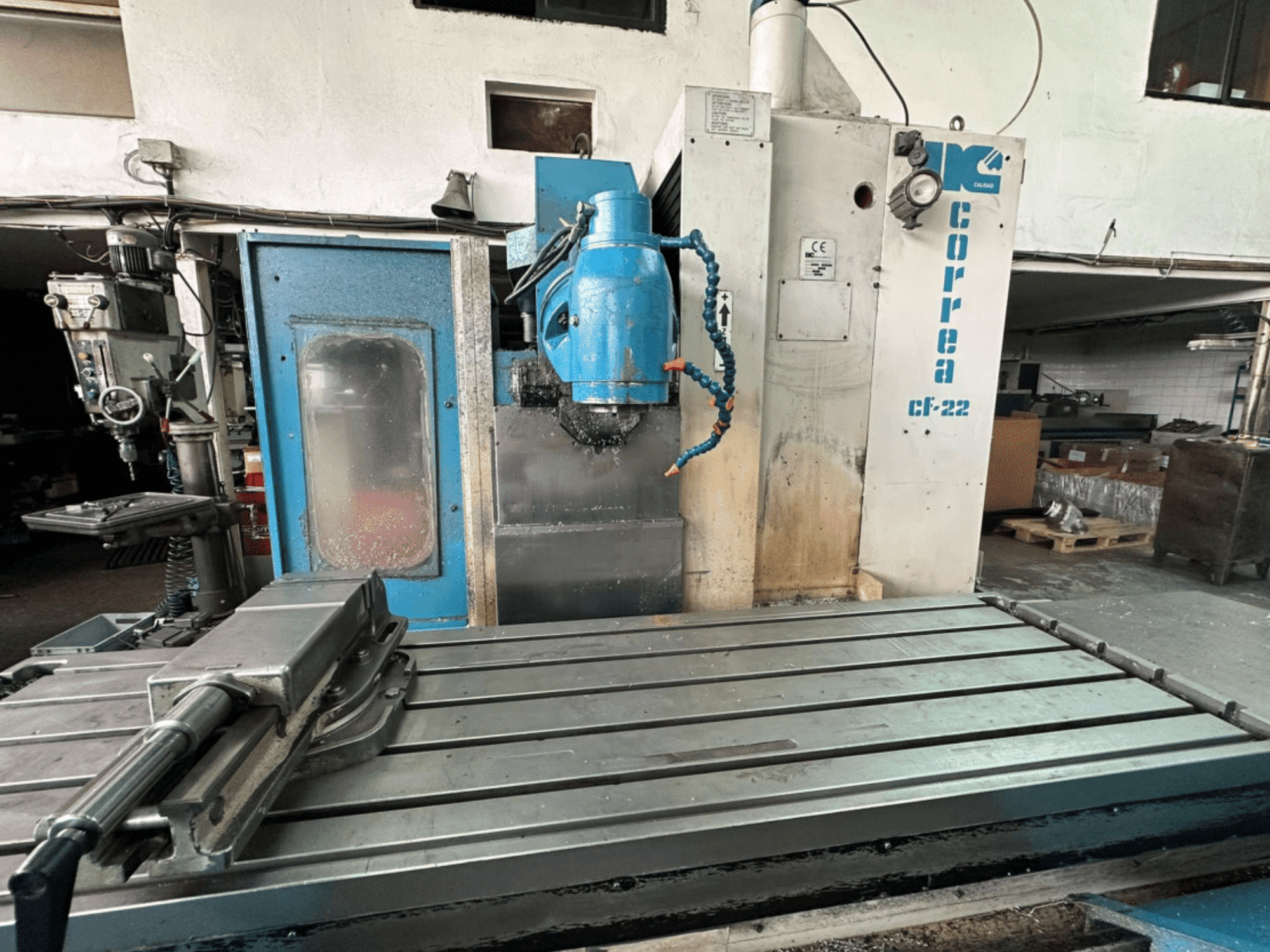 Frézka Correa CF-22 s modrostříbrným designem, posuvným stolem a řeznou hlavou, zobrazená z čelního pohledu.