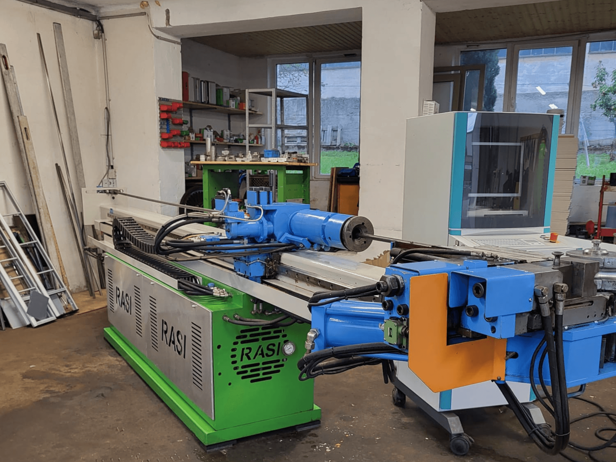 Obráběcí stroj Rasi S 80.6 L G-V3C50 v dílně, boční pohled na modré a zelené komponenty a ovládací panel.