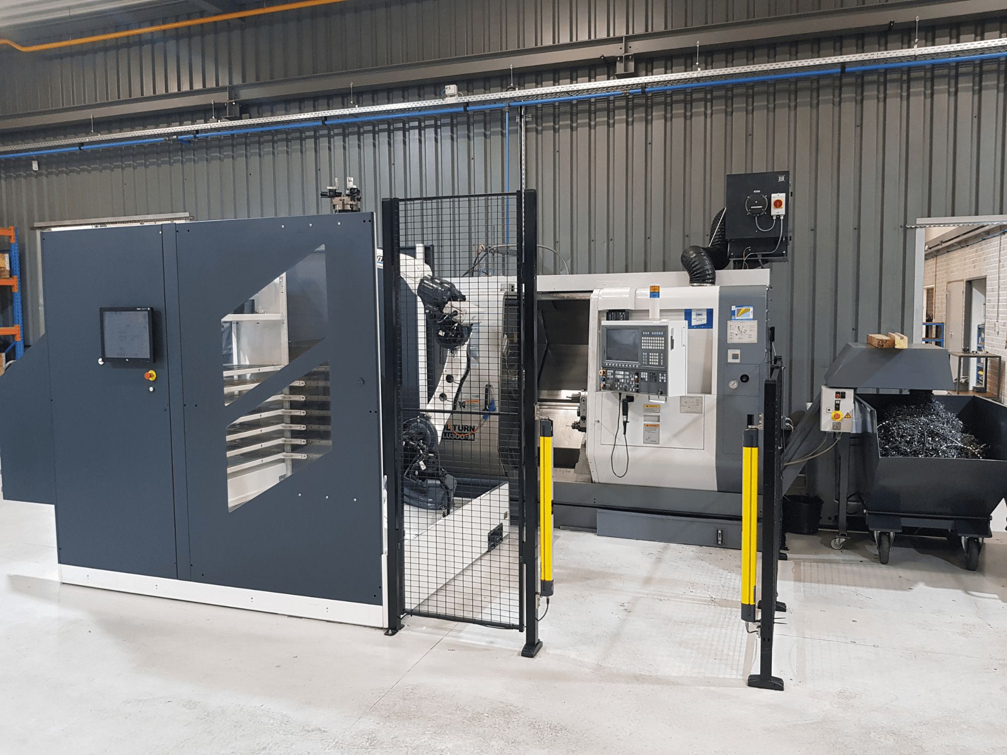 Automatický soustruh a CNC stroj ALTURN v továrním prostředí; pohled zepředu s viditelným ovládacím panelem a bezpečnostním oplocením.