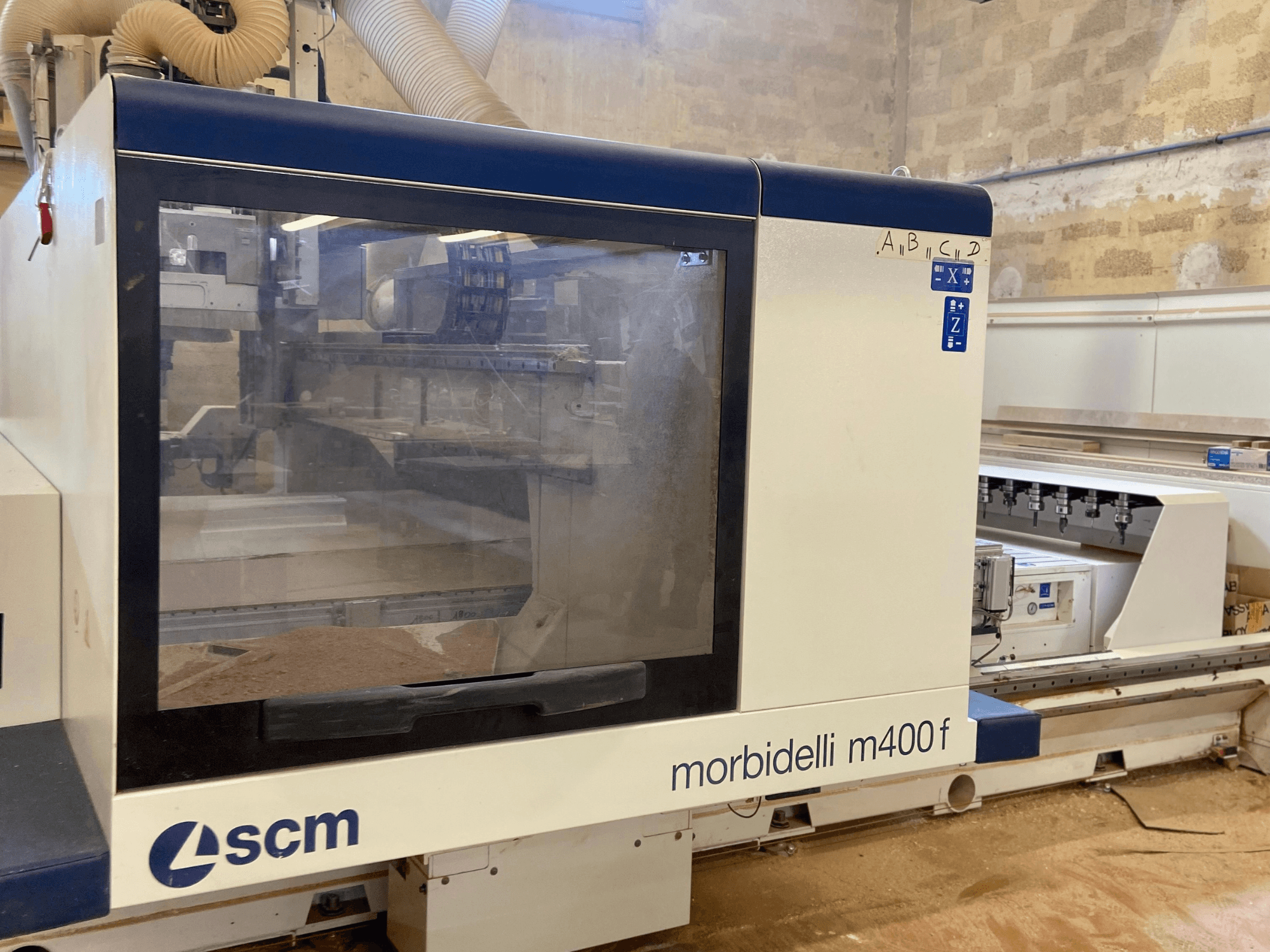 Stroj SCM Morbidelli M400F CNC, pohled zepředu, s ovládacím panelem a viditelnými pilinami na podlaze.