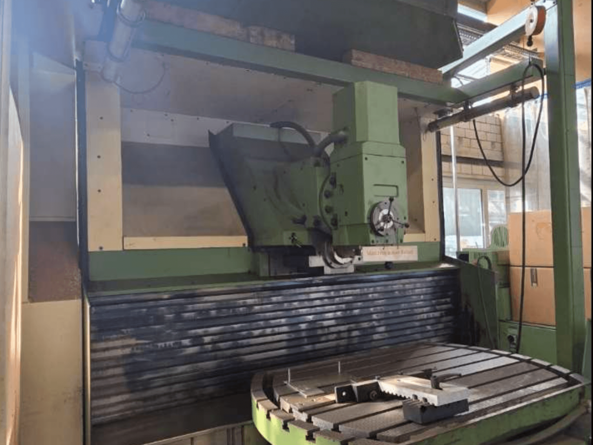 Univerzální obráběcí centrum MAHO MH1000 C v čelním pohledu, na kterém je vidět zelená konstrukce, vřeteno a otočný stůl s obrobkem.