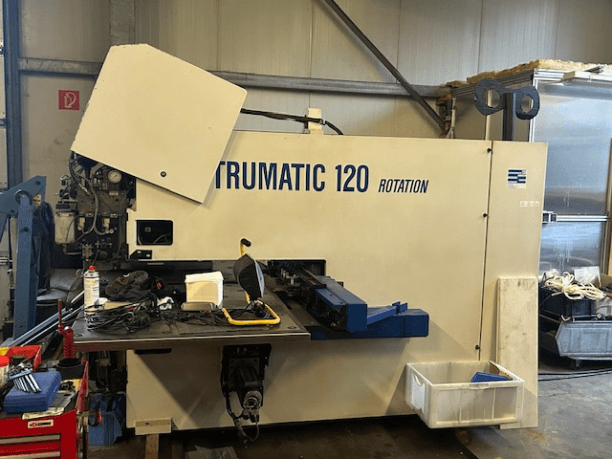 Děrovací stroj TRUMPF Trumatic 120R CNC v dílně, pohled zepředu ukazuje ovládací panel a nástroje na stole.