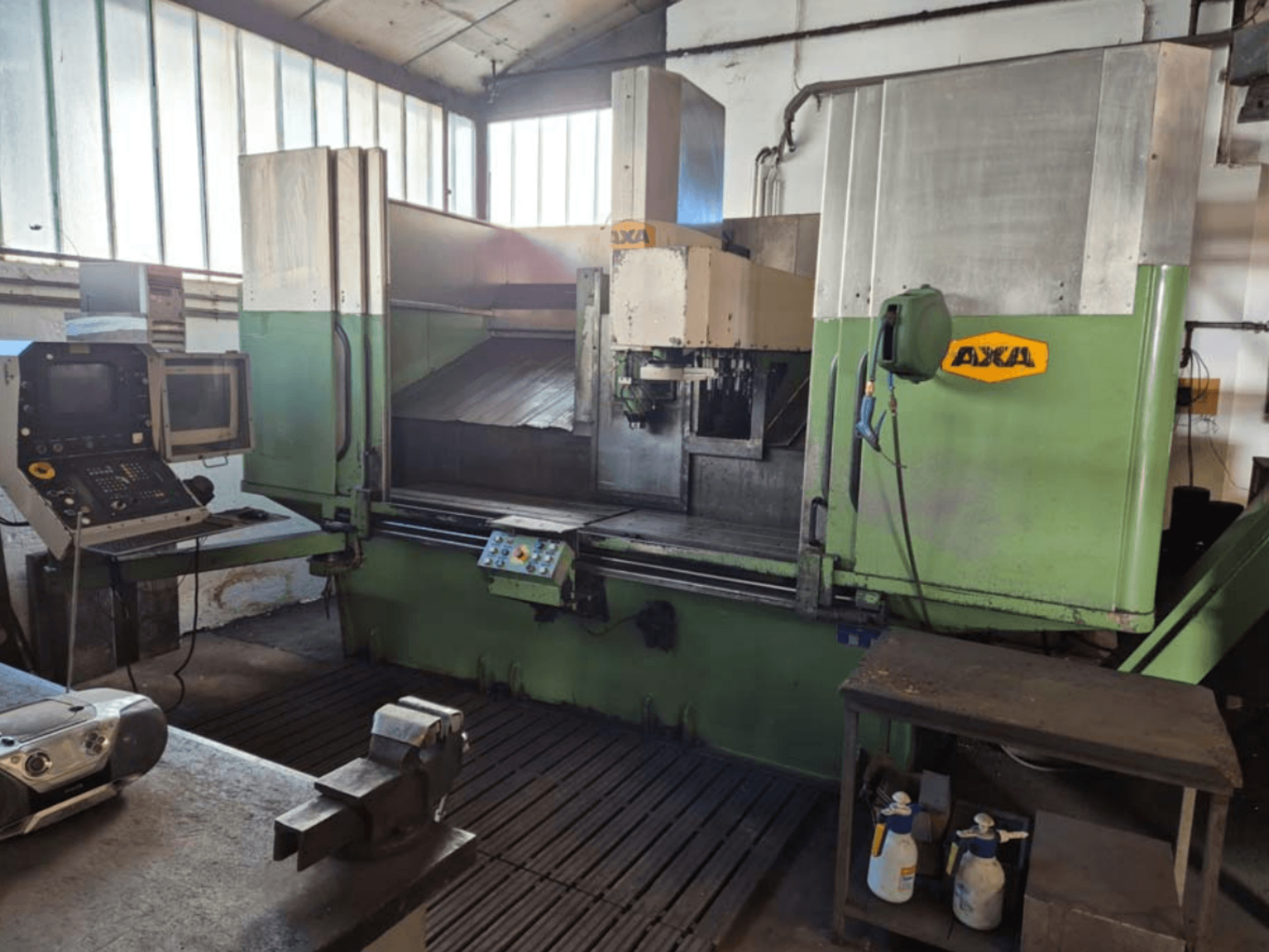 Vertikální obráběcí centrum AXA VSC-2M, pohled zepředu, ovládací panel a pracovní plocha s řeznými nástroji a čisticími prostředky.