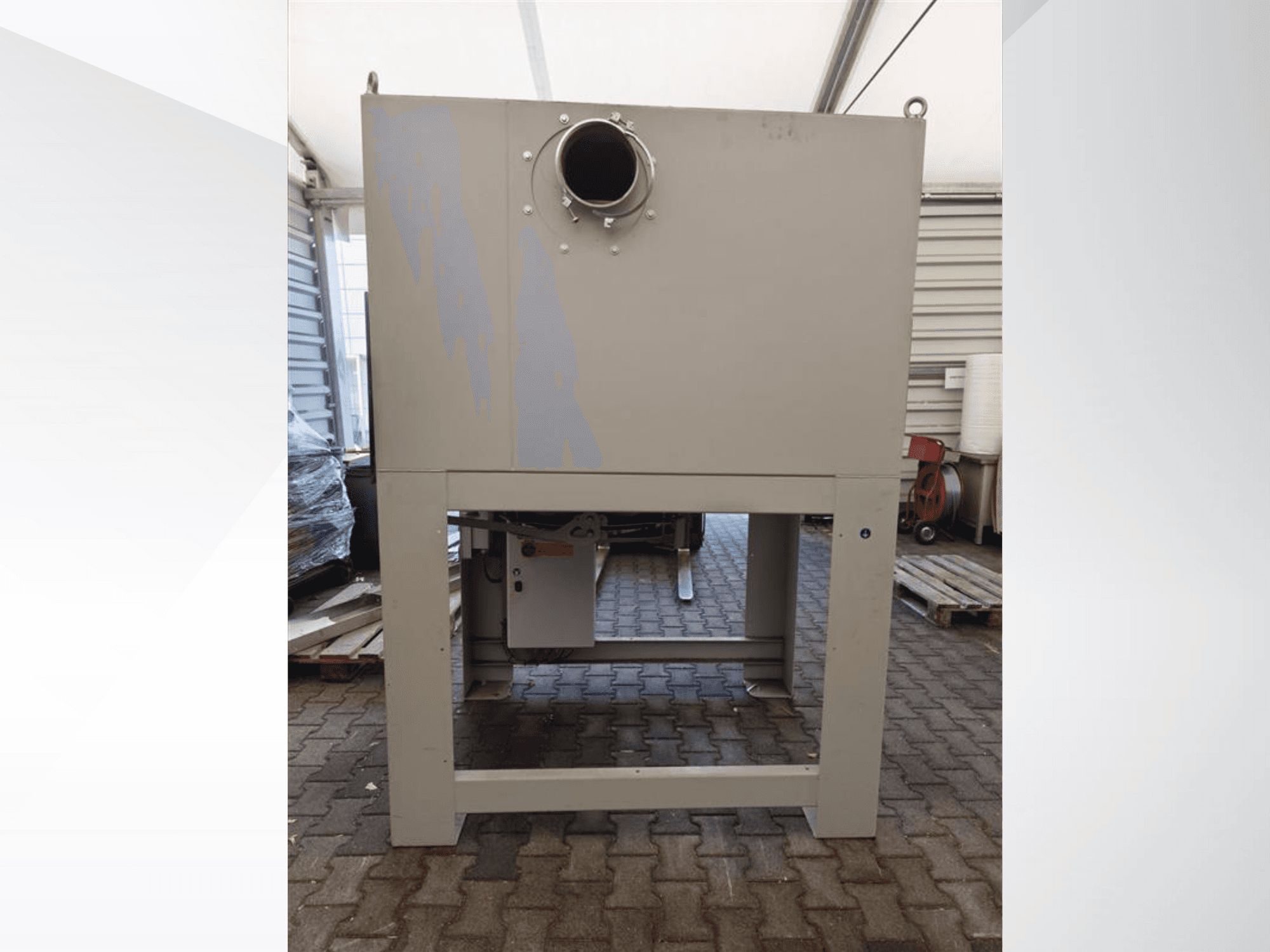 Šedý průmyslový odlučovač prachu při pohledu zepředu, s velkým kulatým otvorem a namontovaný na robustní základně.