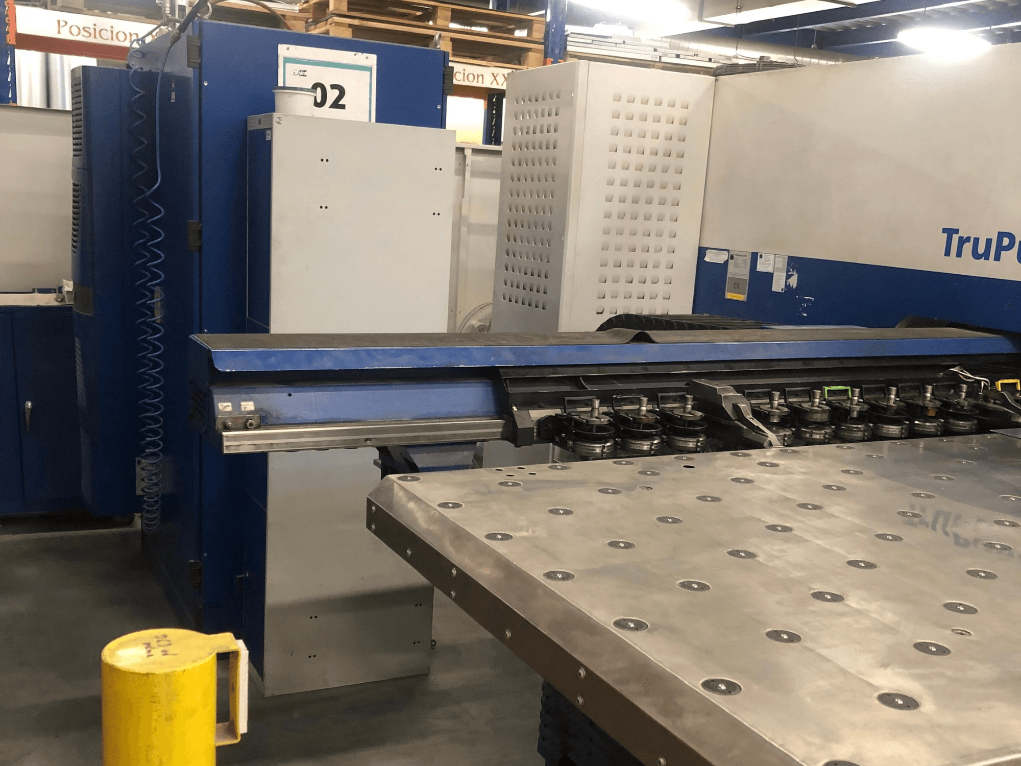 CNC děrovací stroj TRUMPF TruPunch 5000, pohled zepředu znázorňující nástrojovou revolverovou hlavu a ovládací panel, s kovovým pracovním stolem v pozadí.