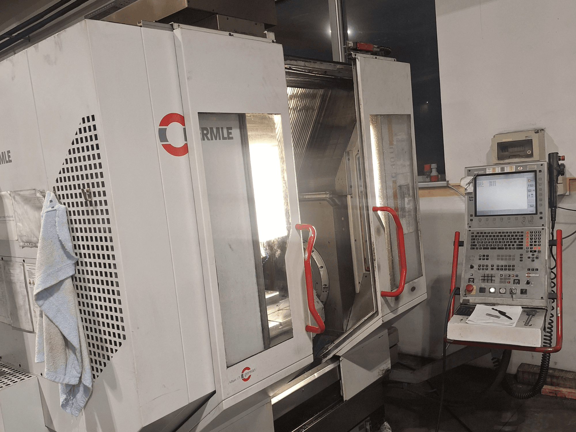 CNC stroj značky Cormile, pohled zepředu ukazuje částečně otevřené dveře a ovládací panel s obrazovkou a tlačítky.