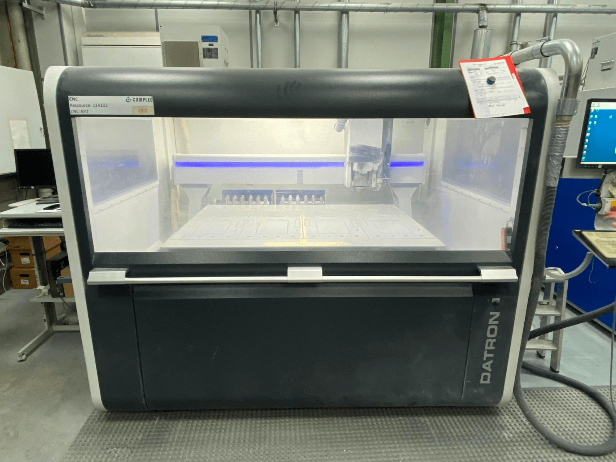 Pohled zepředu na vertikální obráběcí centrum Datron MLCube B s viditelnými ovládacími prvky a pracovním stolem v dílně.