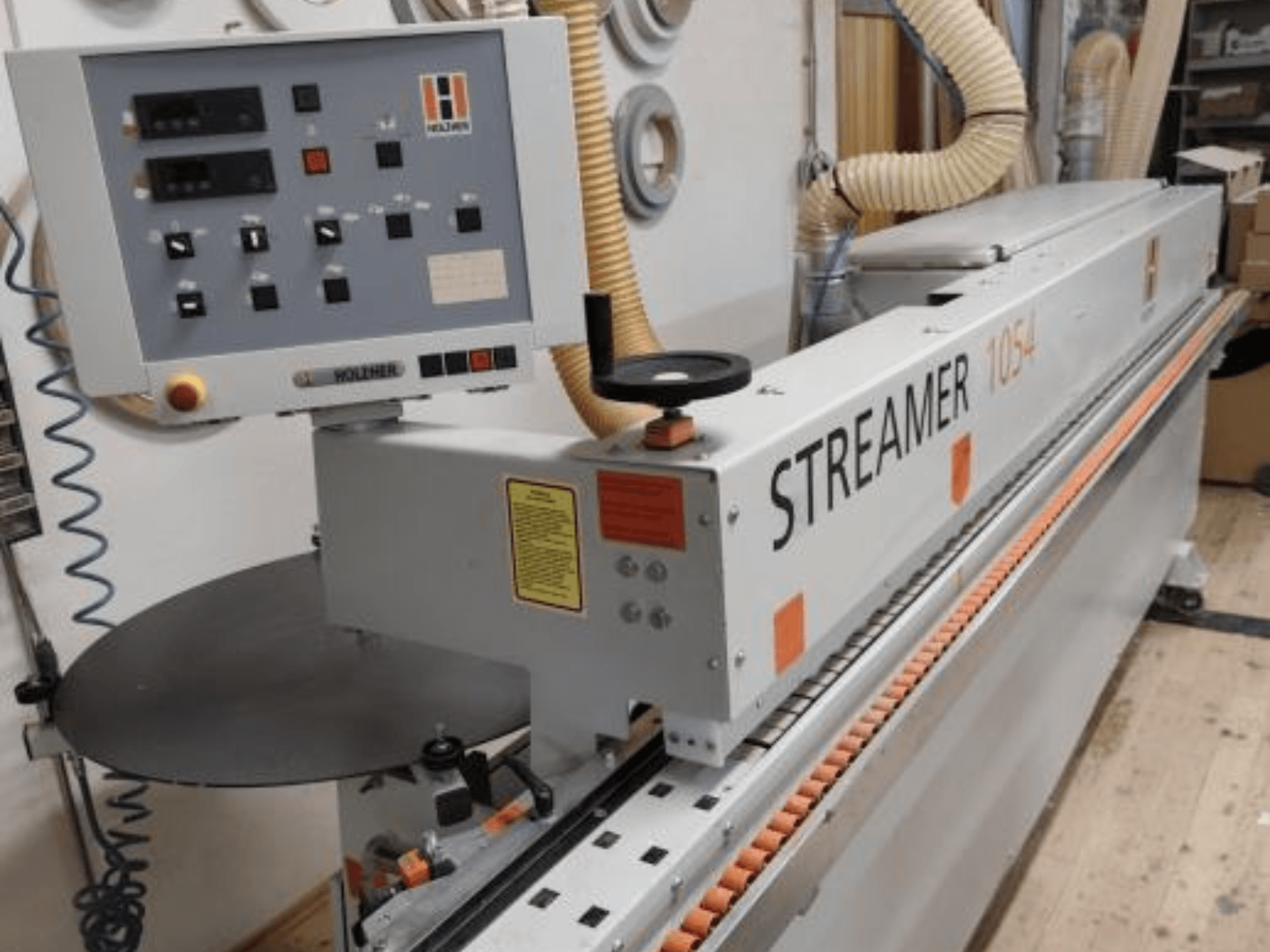 HOLZHER Streamer 1054, boční pohled na ovládací panel a podávací systém na pozadí dílny.