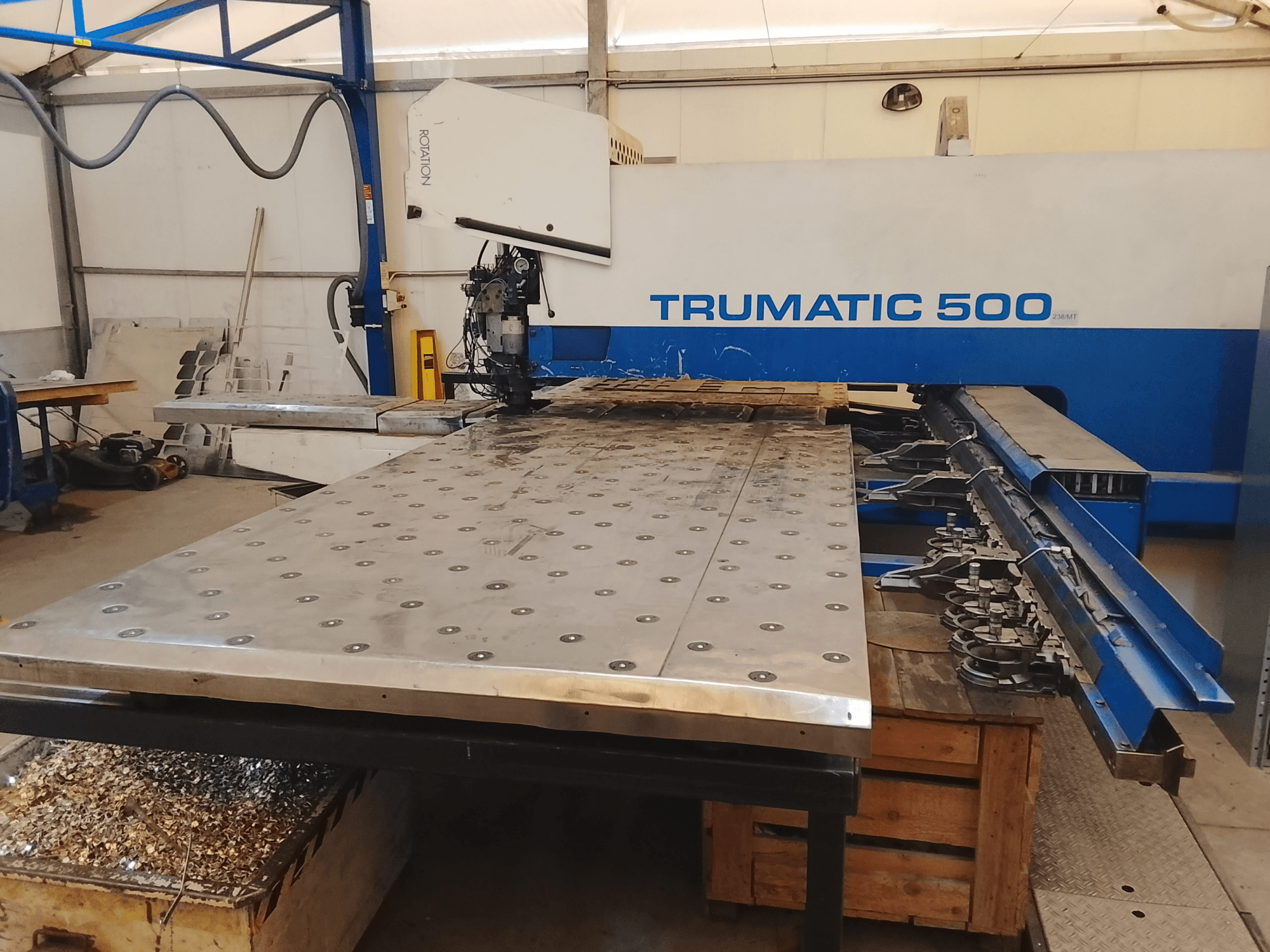 Stroj Trumatic 500 CNC, pohled shora, s velkým kovovým řezacím stolem s namontovanými nástroji a hoblinami pod ním.