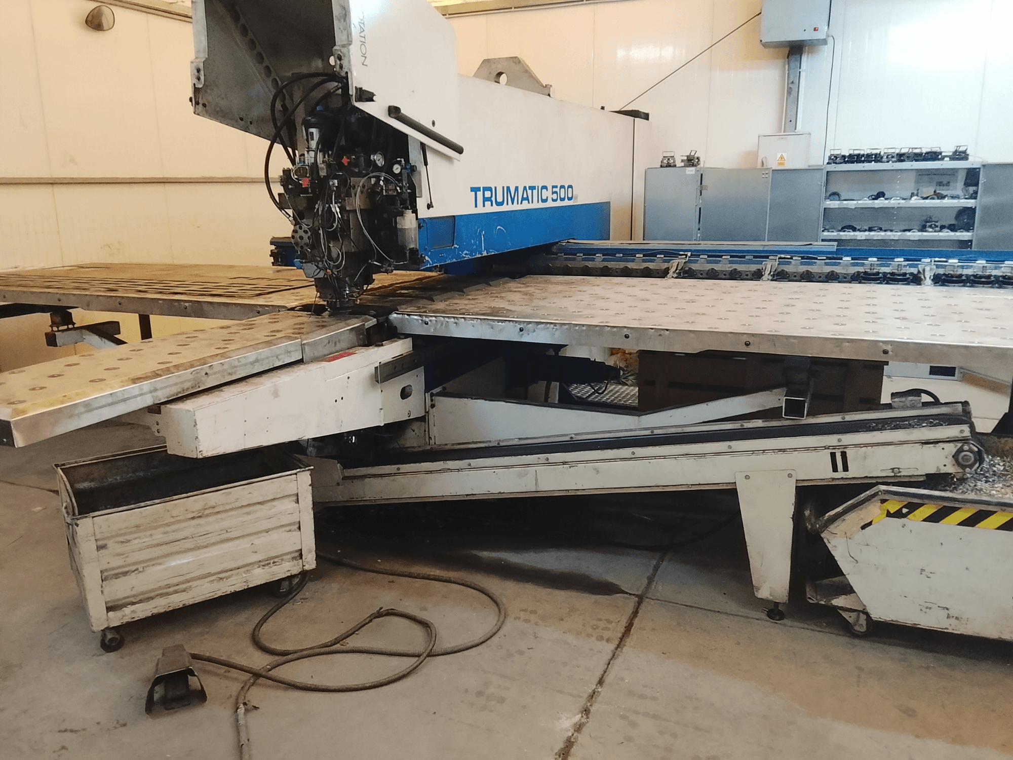 CNC stroj TRUMATIC 500 v dílně, boční pohled na řezací hlavu a kovový pracovní stůl s předvrtanými otvory.