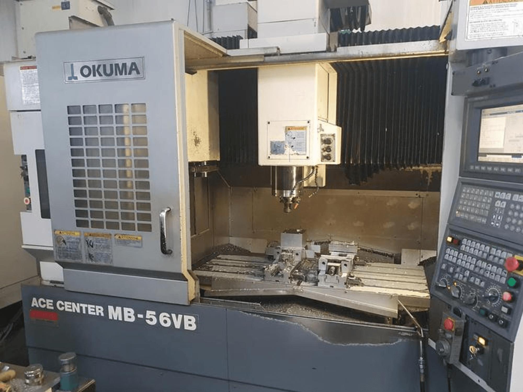 CNC frézka Okuma ACE CENTER MB-56VB z čelního pohledu, na které je vidět ovládací panel a obráběcí prostor.