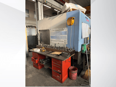 Obráběcí centrum Doosan s červeným pracovním stolem a úložným prostorem, na kterém jsou vystaveny nástroje a zařízení, pohled zepředu.