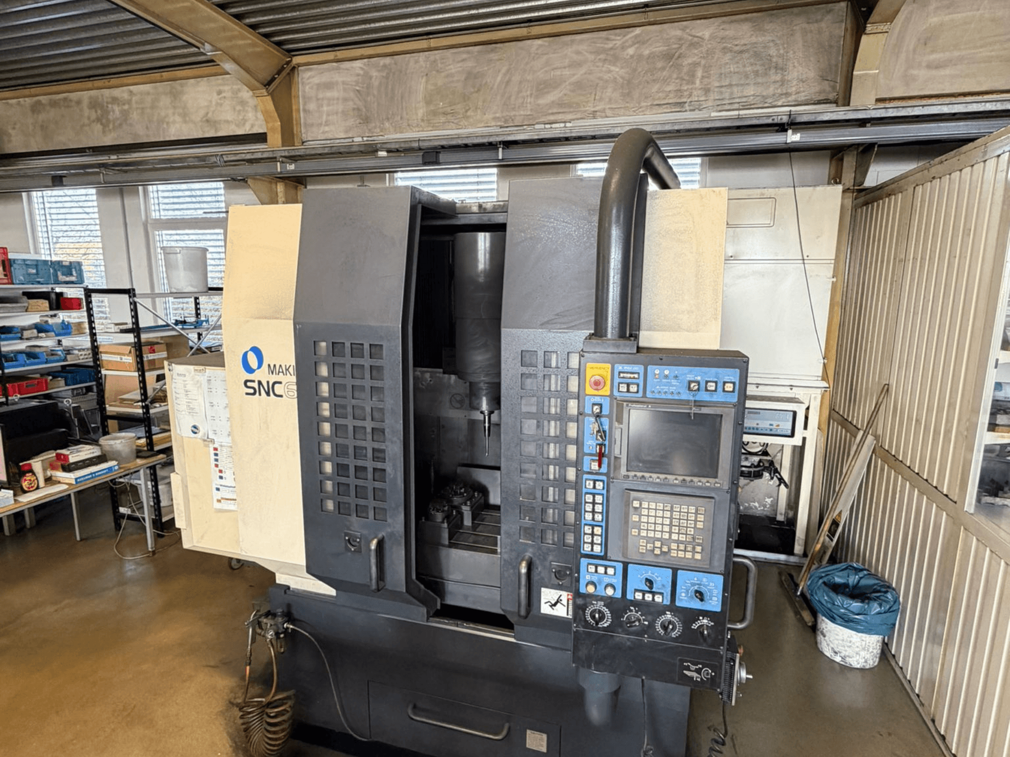 Vertikální obráběcí centrum Makino SNC 64-A15 v čelním pohledu, na kterém je vidět ovládací panel, obráběcí plocha a průmyslový pracovní prostor.