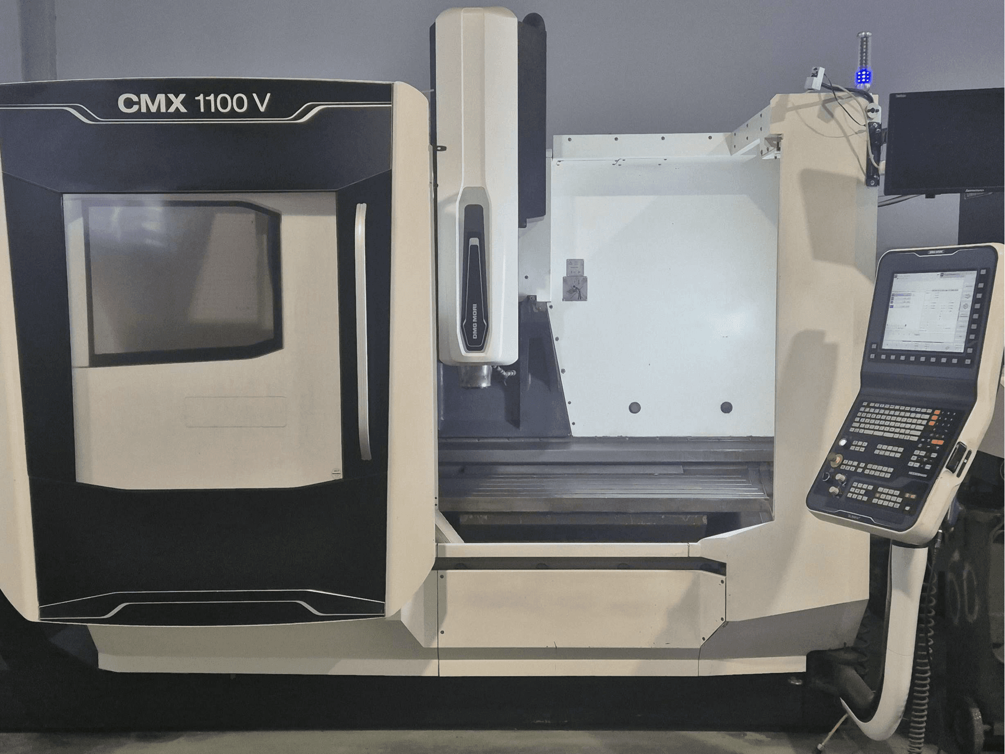 Vertikální obráběcí centrum DMG MORI CMX 1100 V, pohled zepředu s ovládacím panelem a ložem stroje.