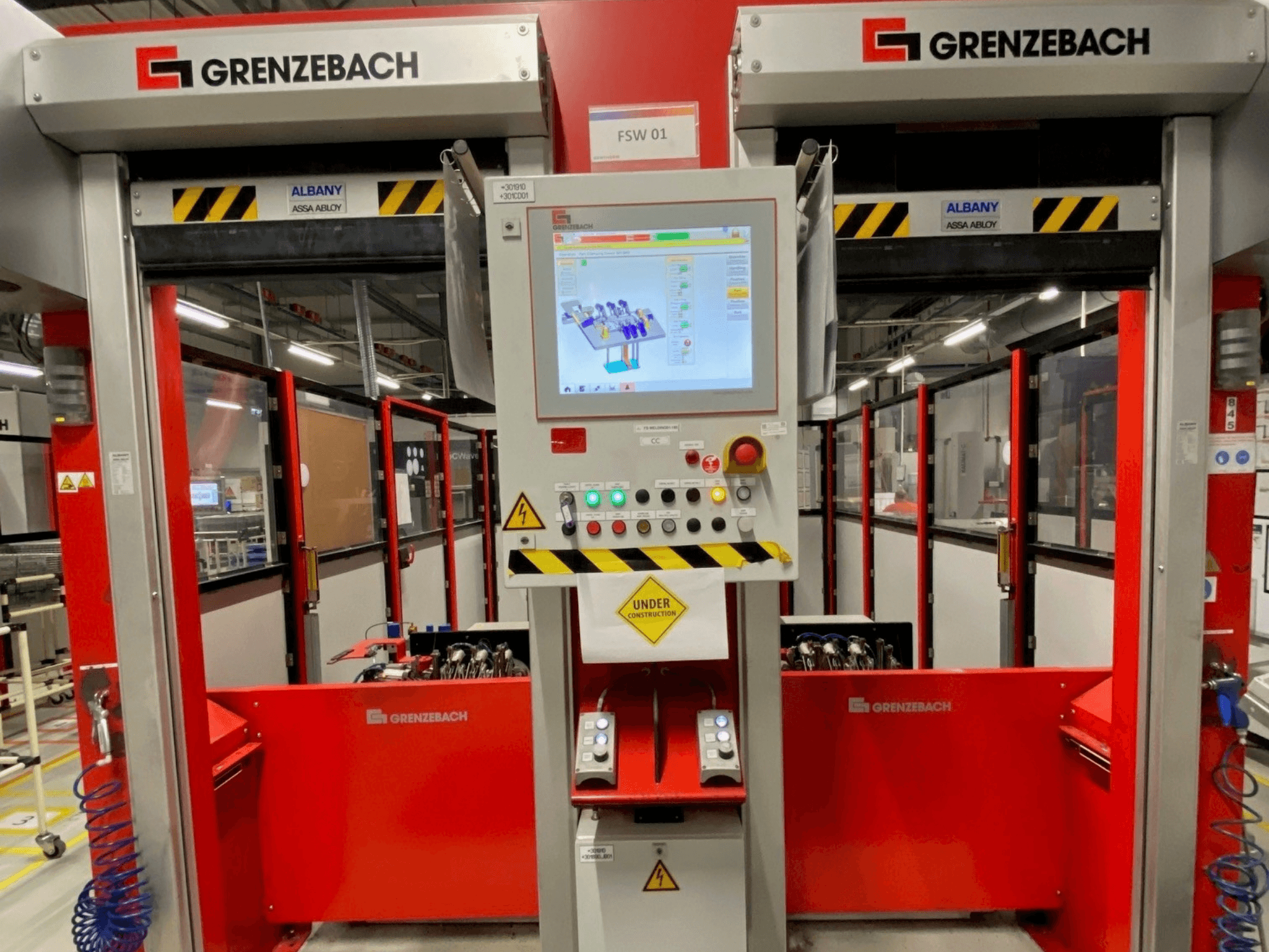 Pohled zepředu na robotické rameno GRENZEBACH FSW GenRob 01 s ovládacím panelem vybaveným dotykovým displejem a různými ovládacími tlačítky.