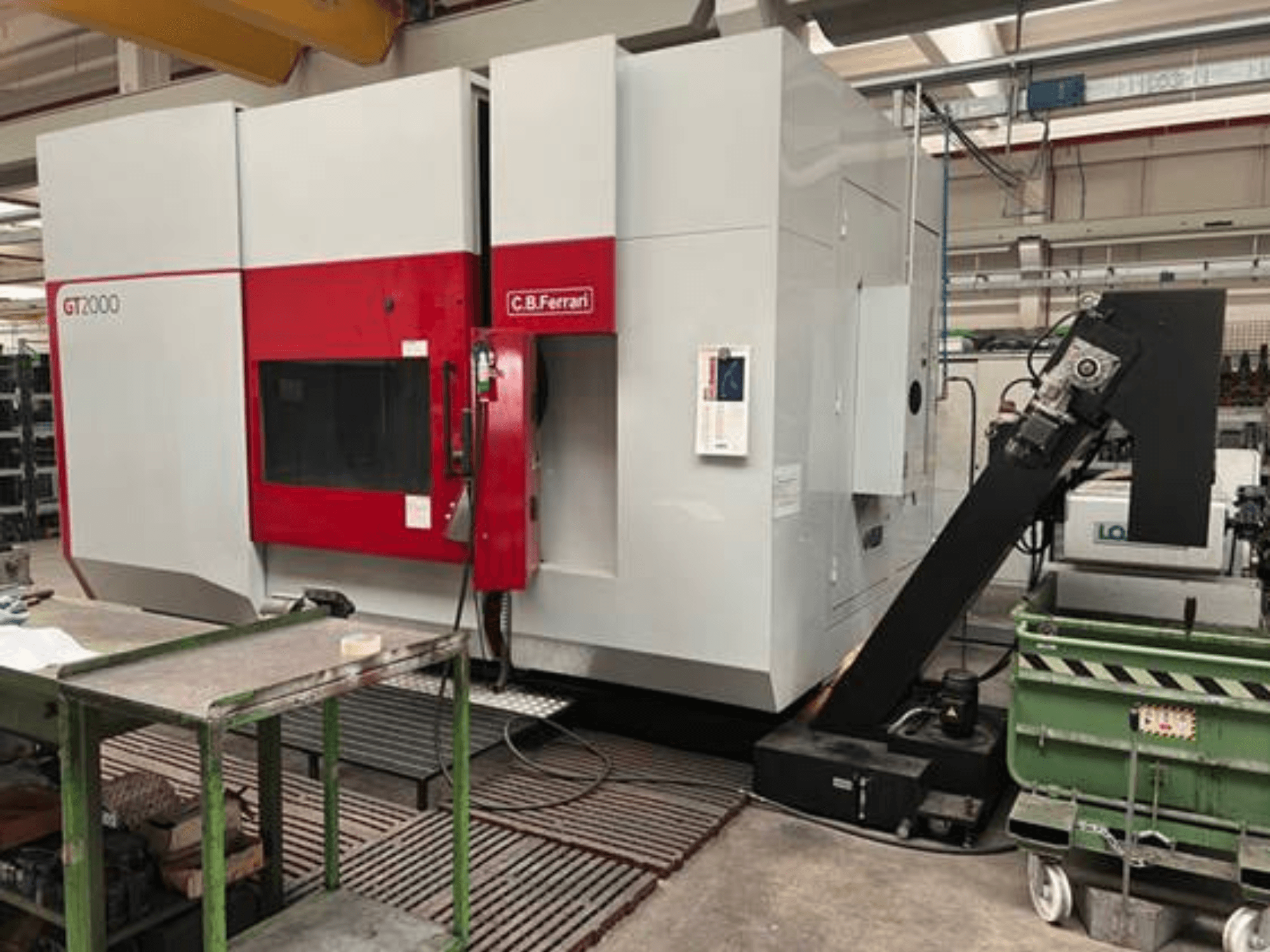 Frézka C.B. Ferrari GT2000 v čelním pohledu, s robotickým ramenem a průmyslovým pracovním prostorem se zeleným vozíkem.