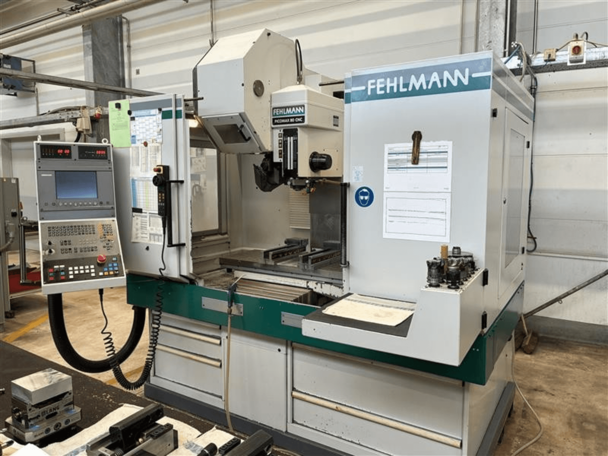 Vertikální obráběcí centrum FEHLMANN PICOMAX 80 CNC-W 2/3 zachycené zepředu, s ovládacím panelem a obráběcím prostorem.