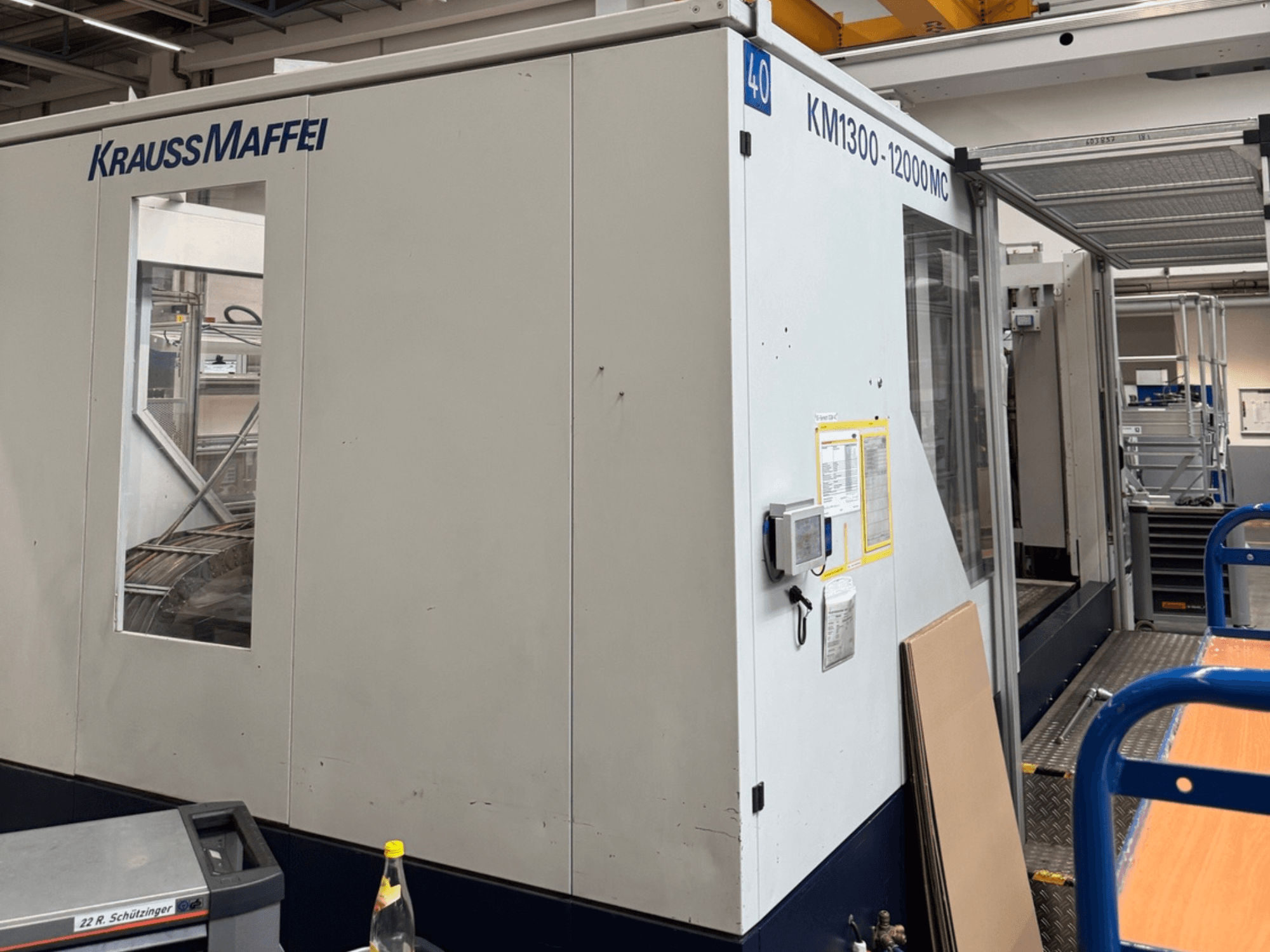Hydraulický vstřikovací stroj Krauss Maffei KM1300-12000 MC, boční pohled na ovládací panel a provozní prostor.