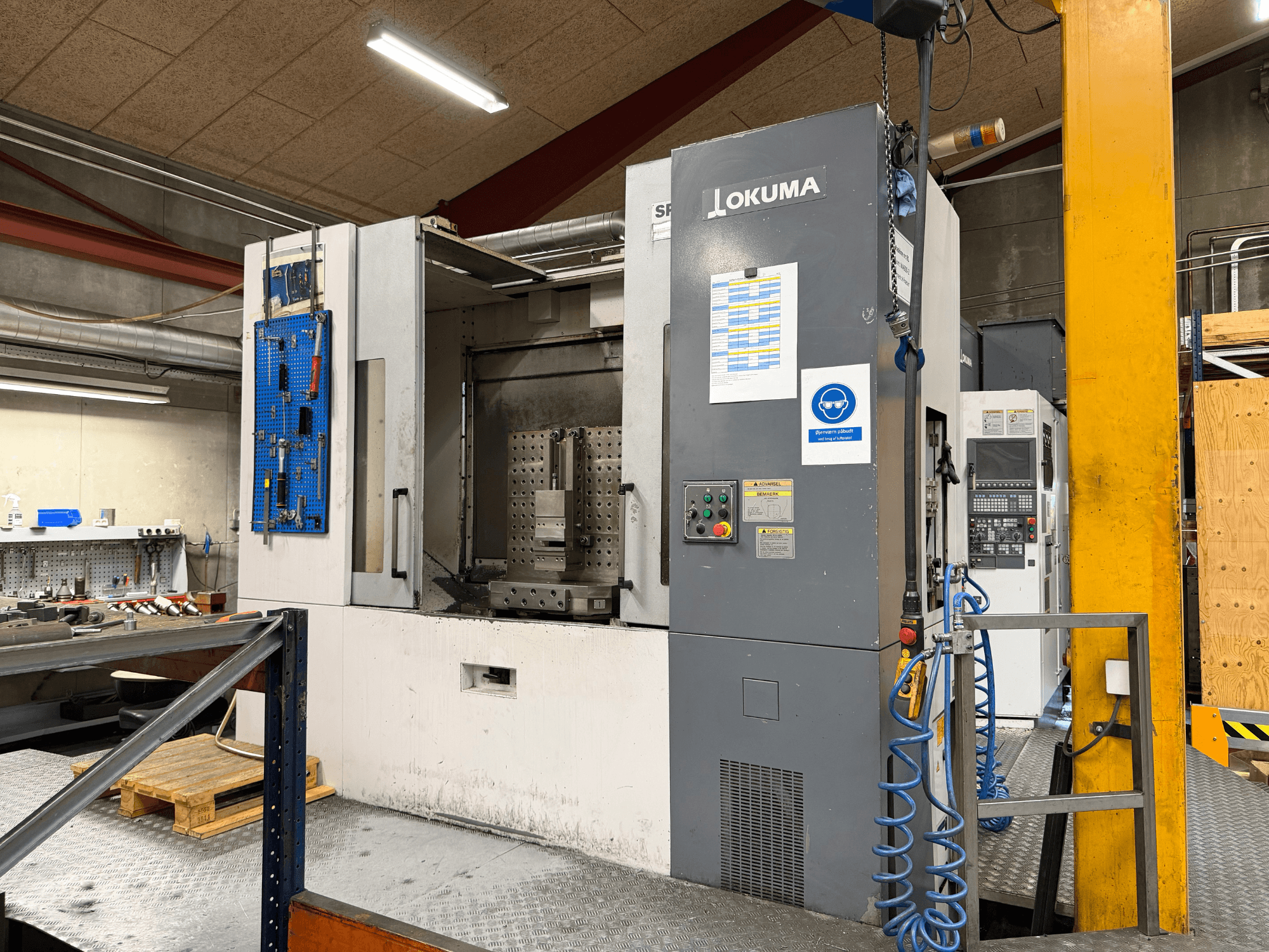 Horizontální obráběcí centrum Okuma MA-600HB v dílně, pohled zepředu s ovládacím panelem a pracovním prostorem.