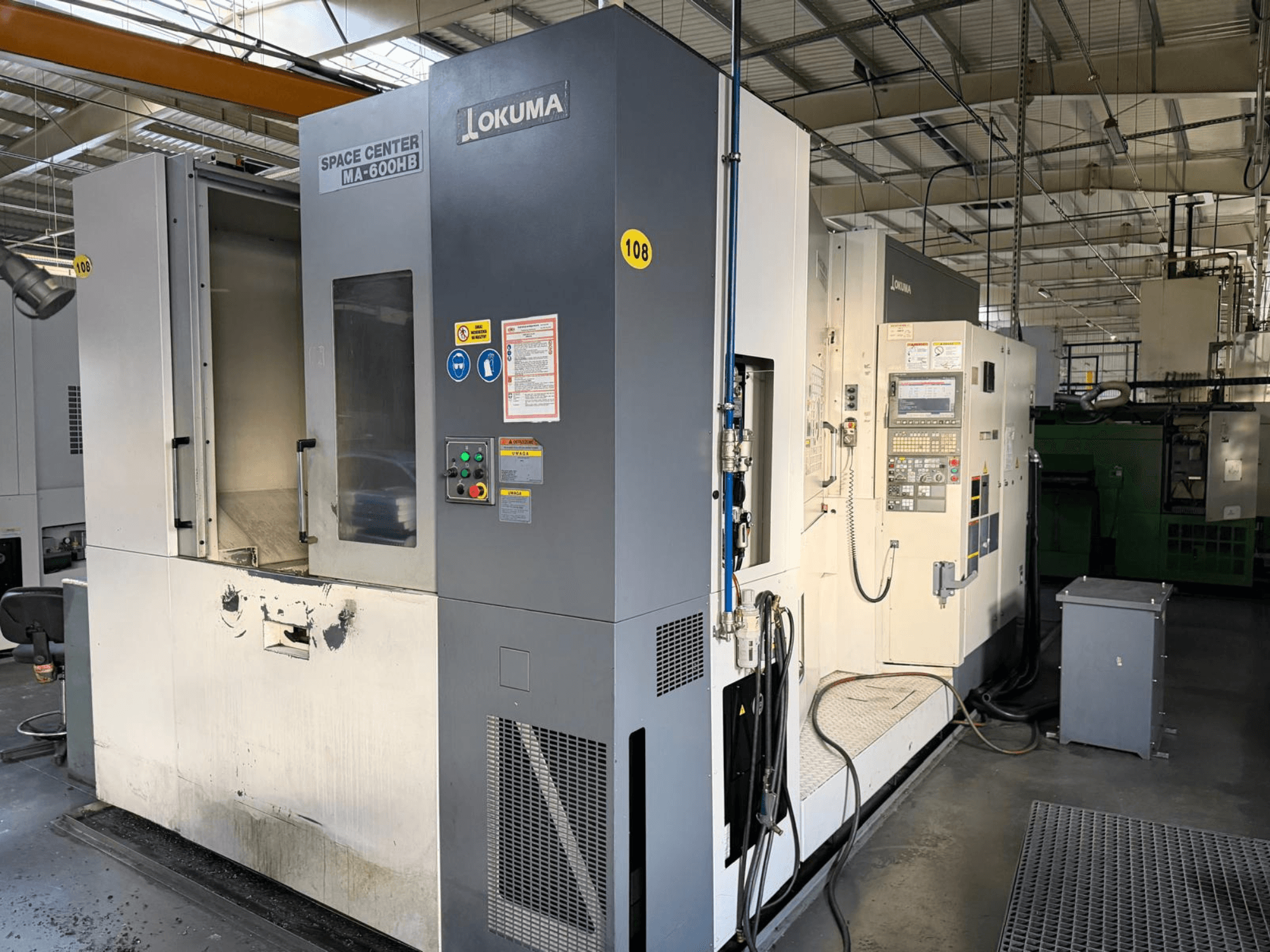 Horizontální obráběcí centrum Okuma MA-600 HB, pohled zepředu na ovládací panel a řeznou plochu s viditelnými stopami opotřebení.