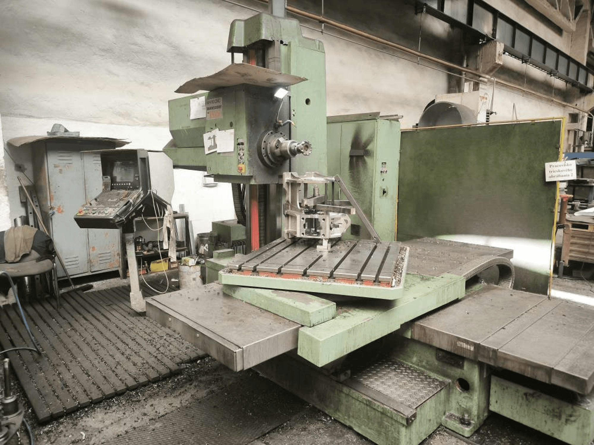 CNC vyvrtávací stroj TOS WH 10 při pohledu zepředu, na kterém je vidět obrobený obrobek na stole a ovládací panel.