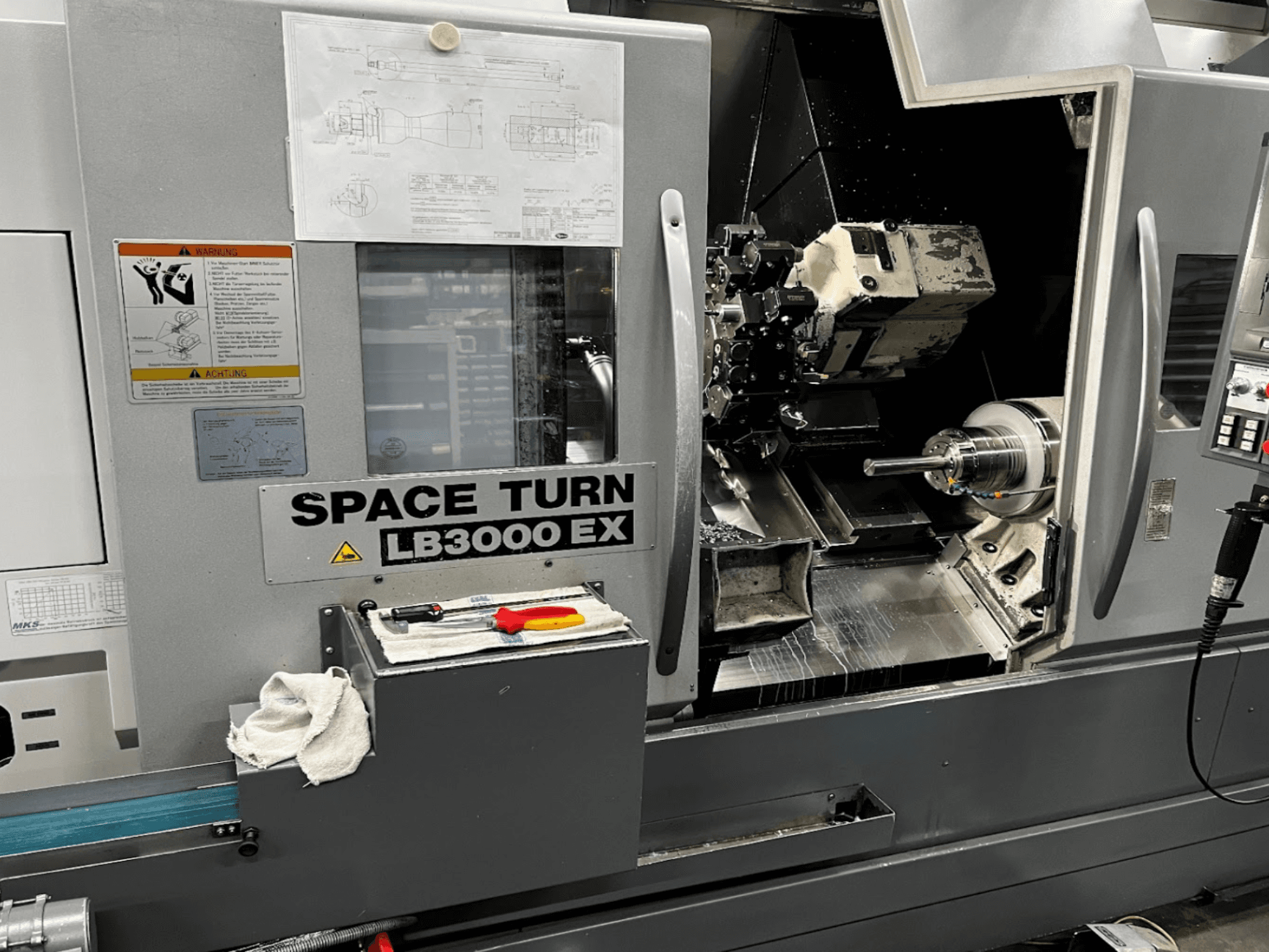 Horizontální soustruh Okuma LB3000EX MYW, pohled zepředu s viditelným ovládacím panelem, nástroji a detaily pracovního prostoru.