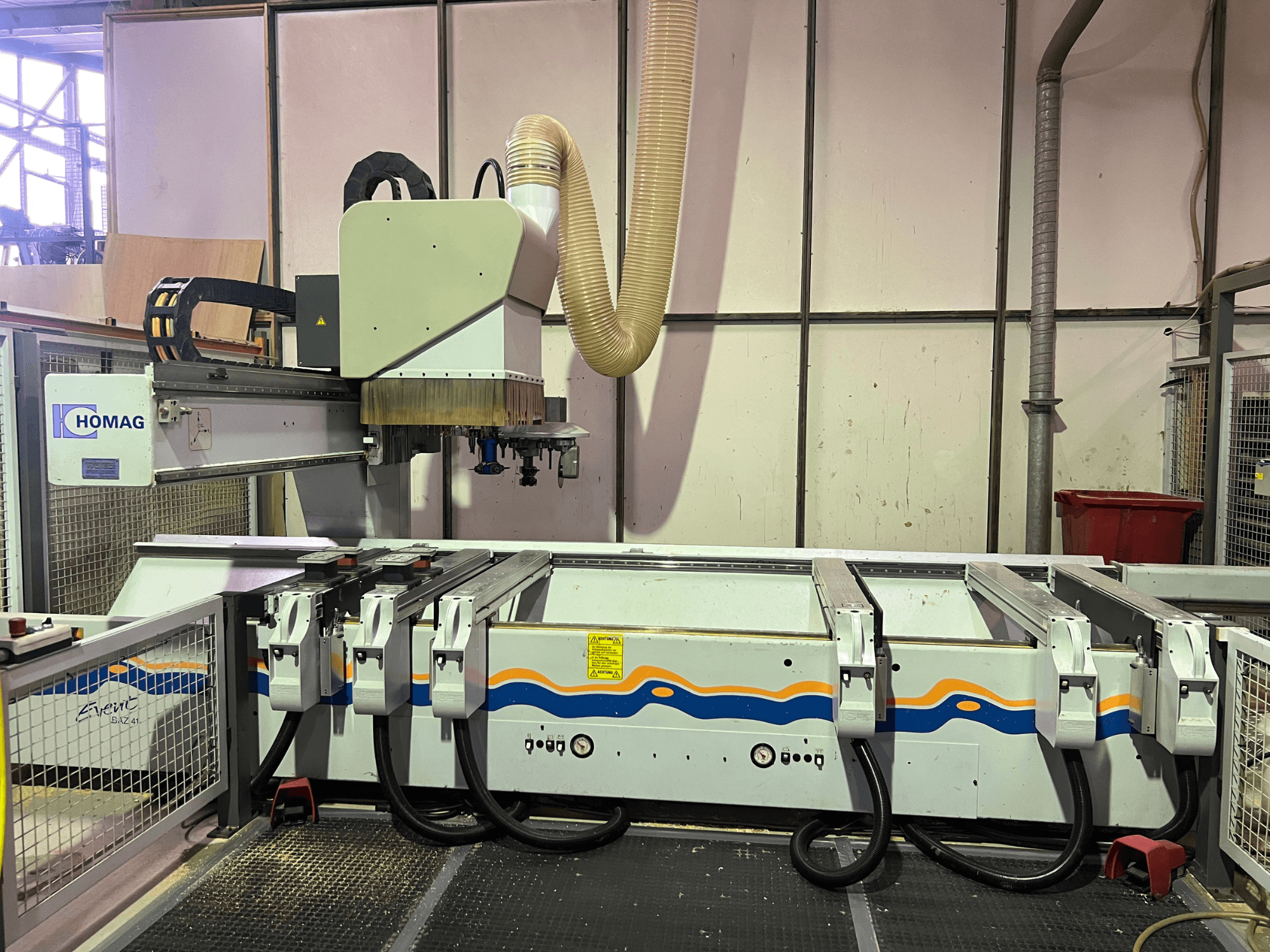 CNC stroj HOMAG BIZ 4 v dílně; pohled zepředu ukazuje systém odsávání prachu a ovládací panel s kabely.