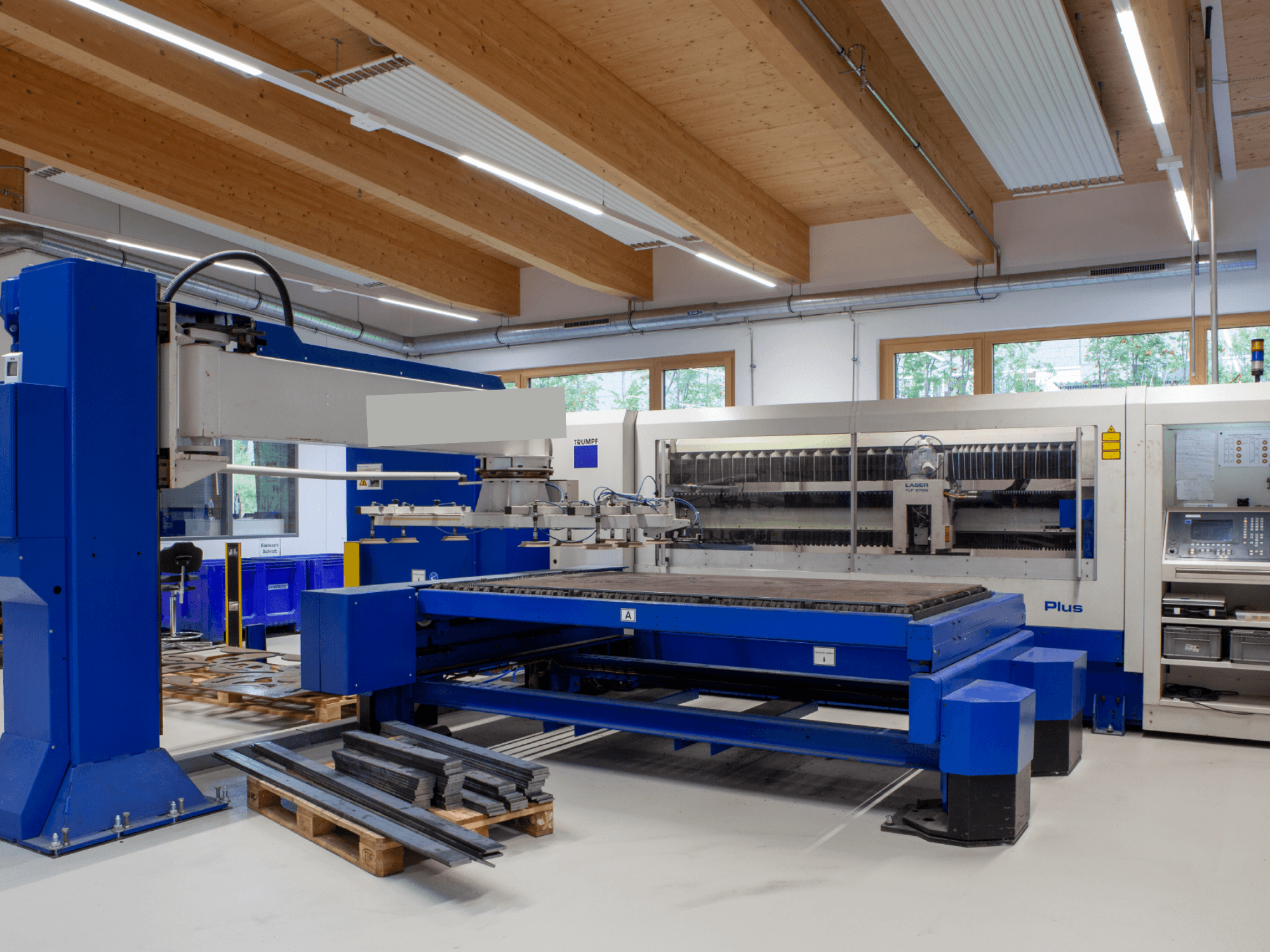 Laserový řezací stroj TRUMPF TRUMATIC L 2530 Plus s CO₂ v dílně, který se vyznačuje velkým řezacím stolem a průmyslovým designem.