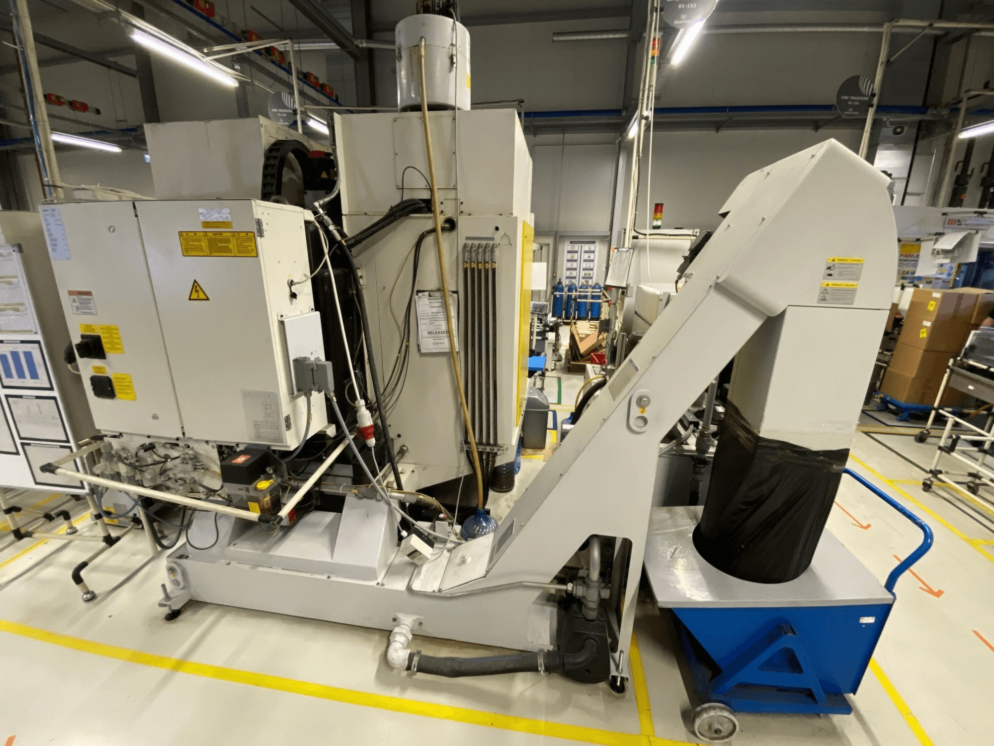 Vertikální obráběcí centrum FANUC ROBODRILL α-D21LiB – pohled zepředu, na kterém jsou vidět elektrické součásti a výstupní žlab.