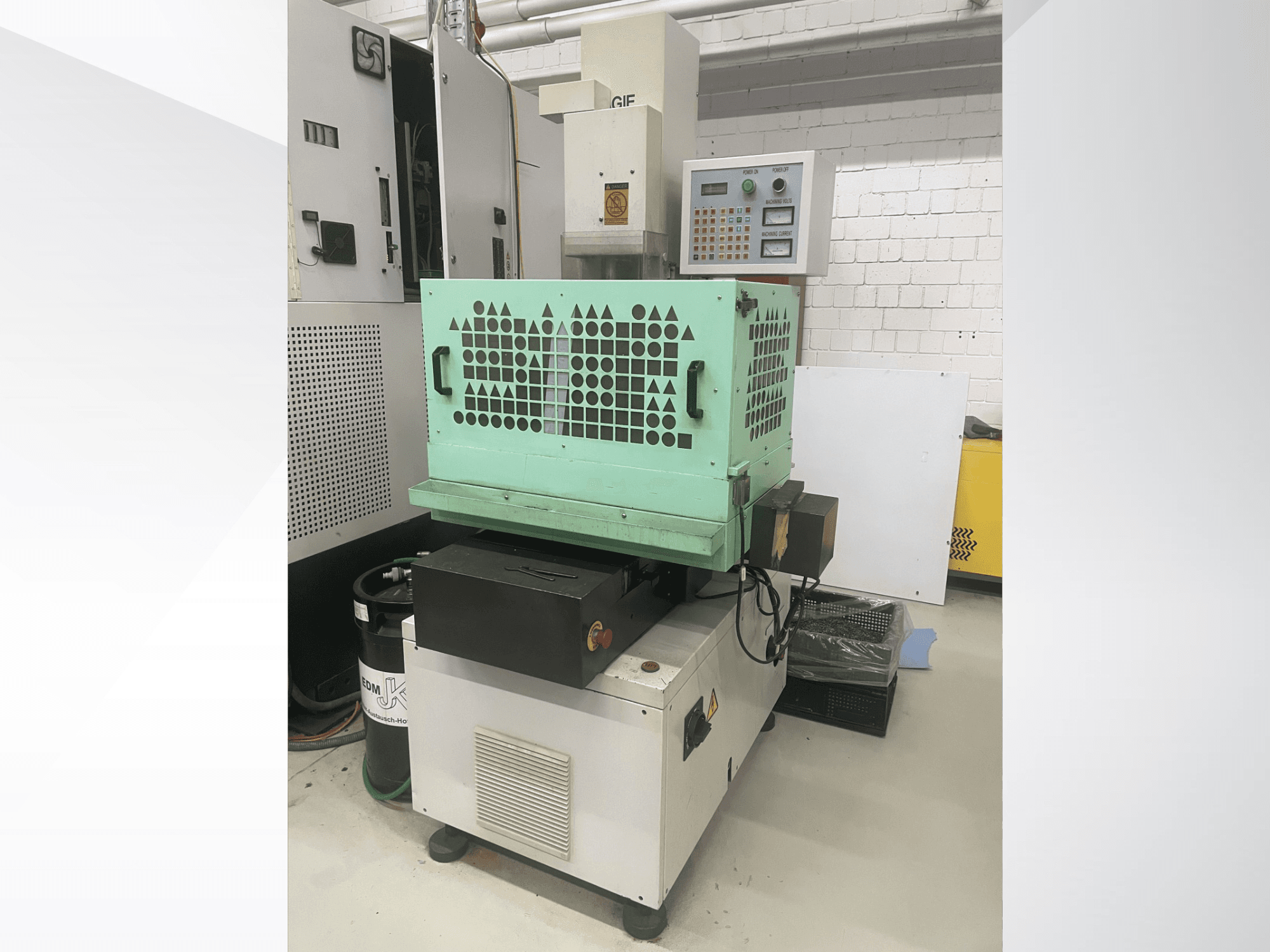 AGIE Drill, kovový vrtací stroj, pohled zepředu ukazuje ovládací prvky, zelený plášť a kompaktní konstrukci. Ideální pro přesné práce.